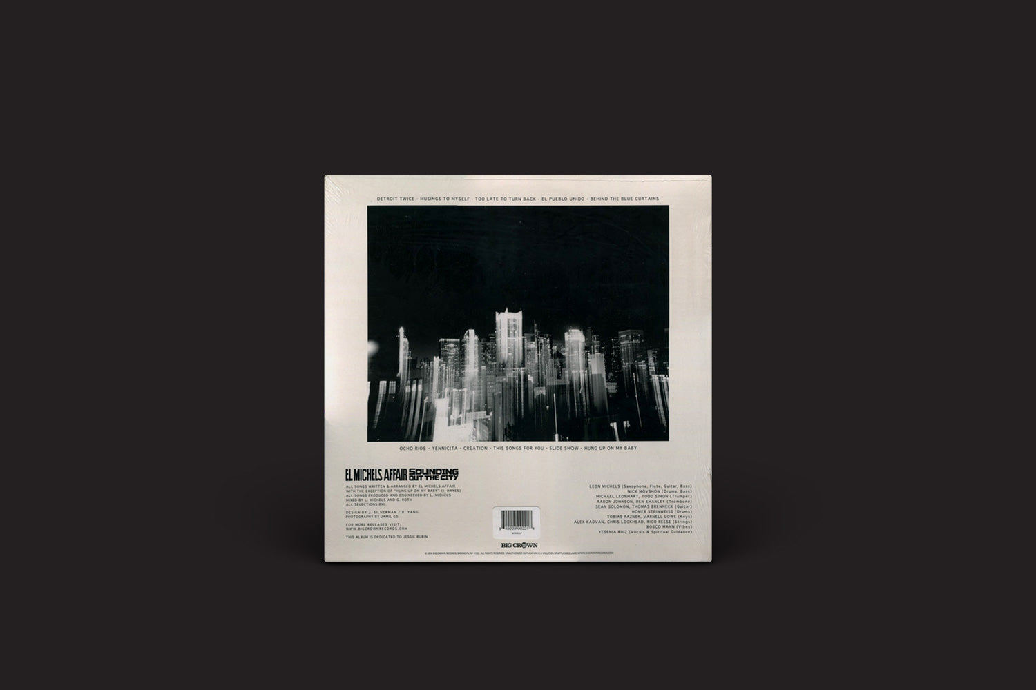 A imagem mostra a contracapa de "Sounding Out The City" do El Michels Affair, lançado pela Big Crown Records. Ela apresenta uma ilustração de paisagem urbana em tons de cinza, cercada por títulos de músicas e créditos, com um fundo de silhueta escura incorporando uma vibe soul retrô e um código de barras na parte inferior.