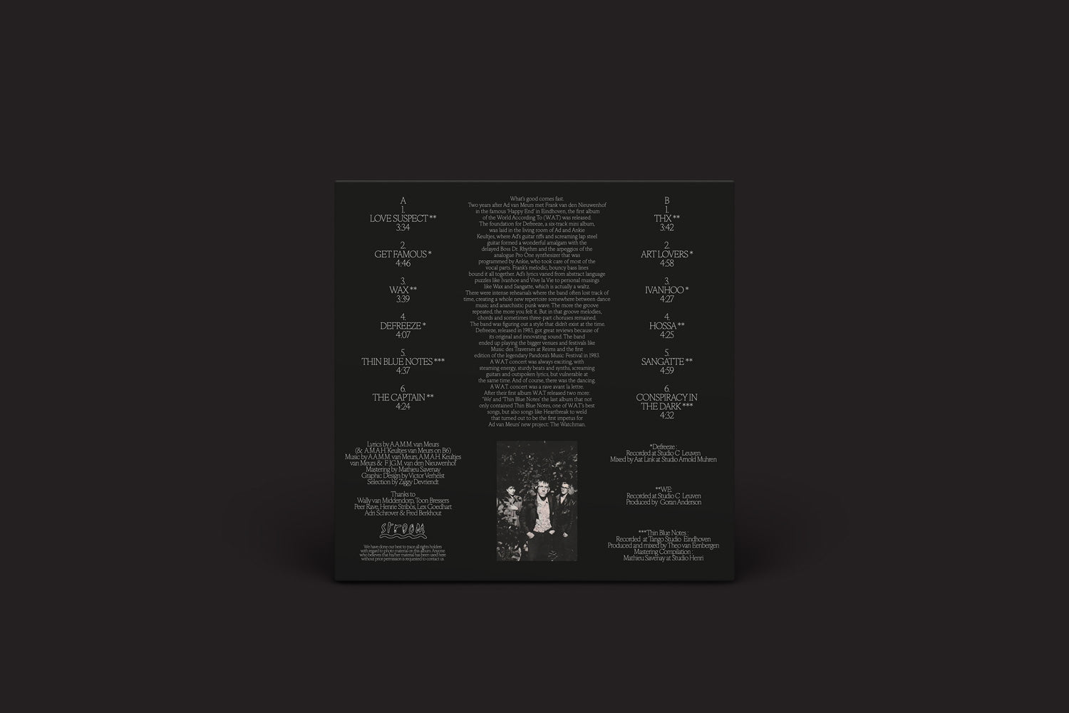 O álbum W.A.T: World According To (Eindhoven 1983-1985) de Stroom apresenta uma capa quadrada escura com títulos de músicas, créditos e letras em branco, além de uma pequena foto em preto e branco de pessoas na parte inferior, ecoando uma vibração punk contra um fundo simples.