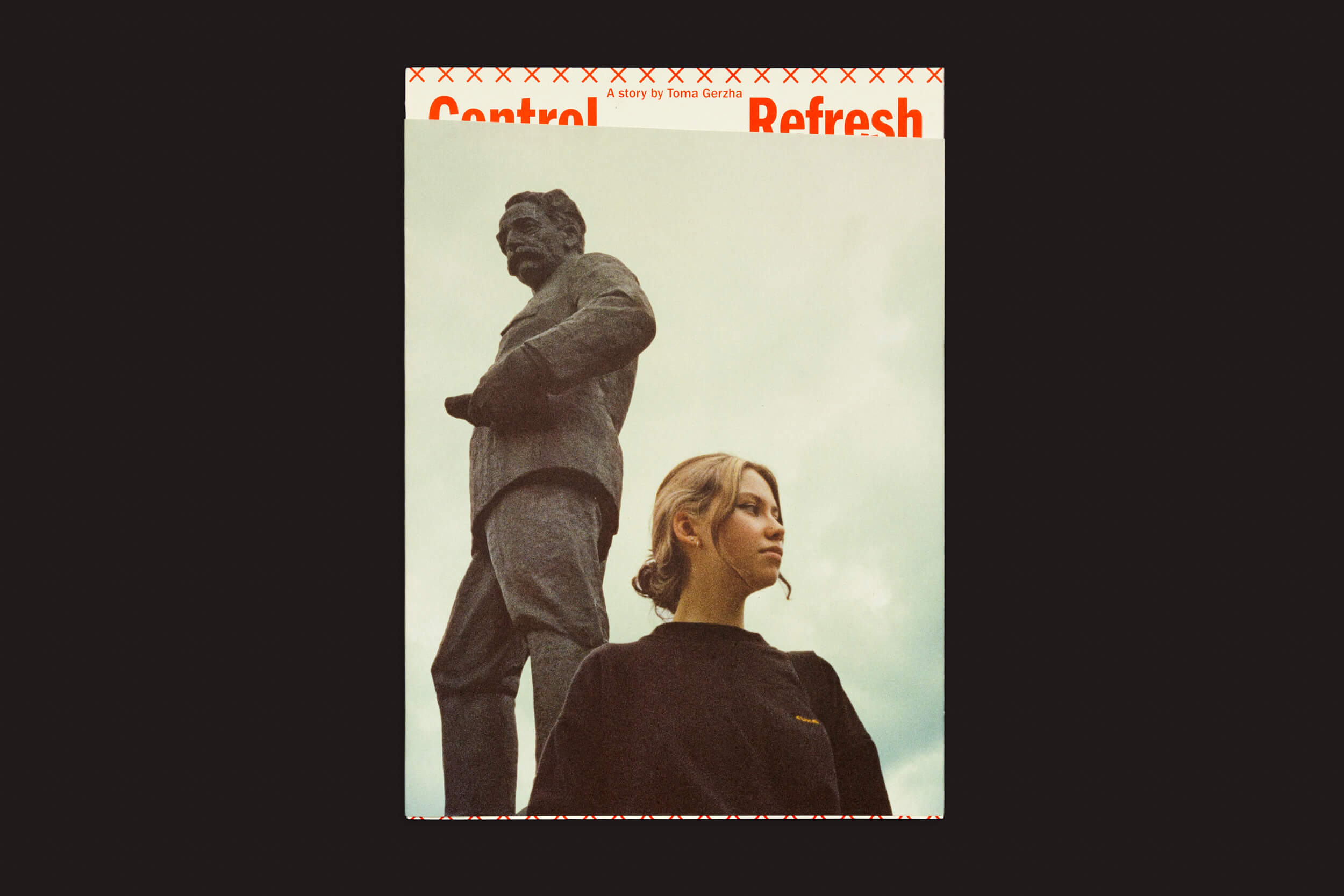 Uma pessoa com cabelos loiros está diante de uma estátua imponente de um homem sob um céu nublado. Texto vermelho sobrepõe o topo, dizendo Control Refresh, refletindo temas frequentemente vistos no trabalho de Toma Gerzha, publicado pela The Eriskay Connection.