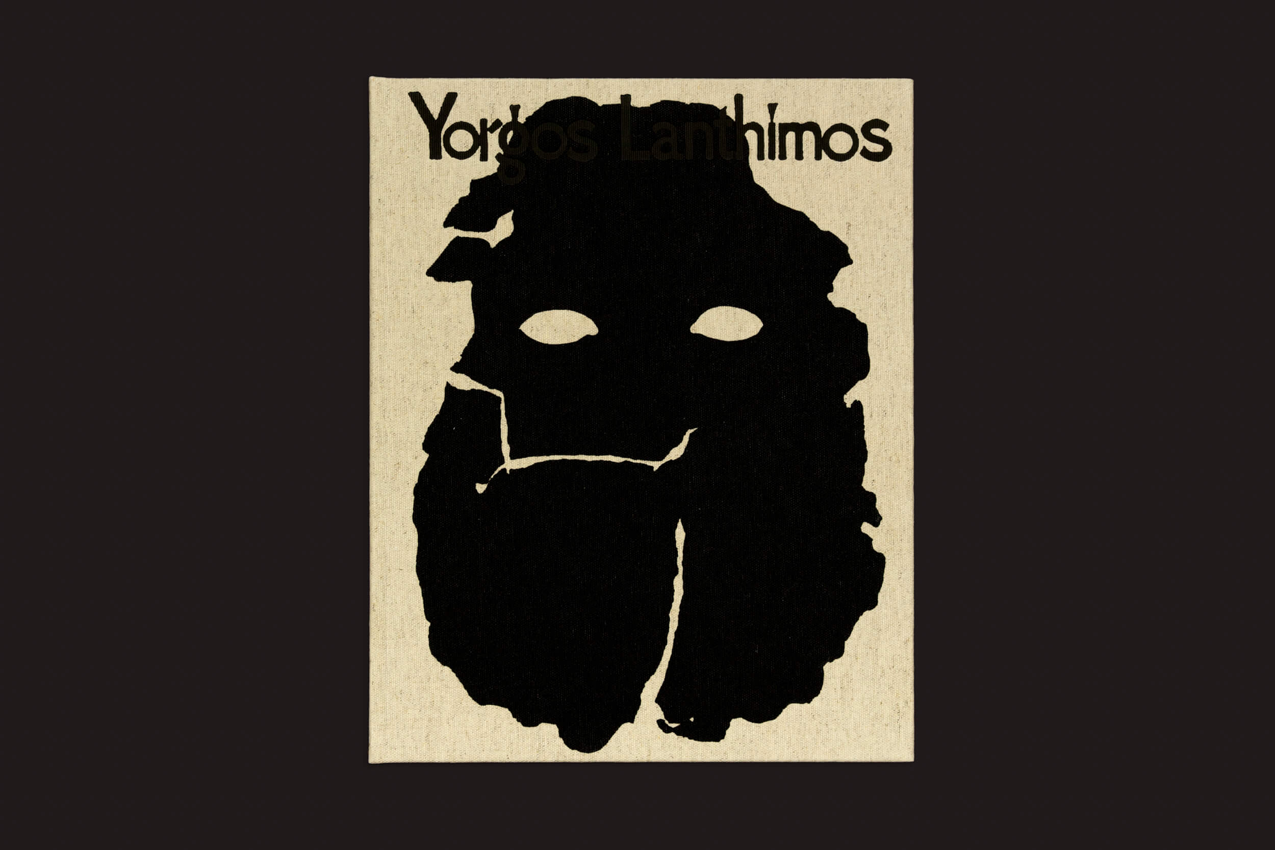 Um pôster gráfico da Void apresenta uma silhueta abstrata preta que lembra uma máscara com buracos para os olhos em um fundo bege, ecoando a arte misteriosa de Yorgos Lanthimos. No topo, o texto preto diz Yorgos Lanthimos: Querido Deus, o Partenon ainda está quebrado.