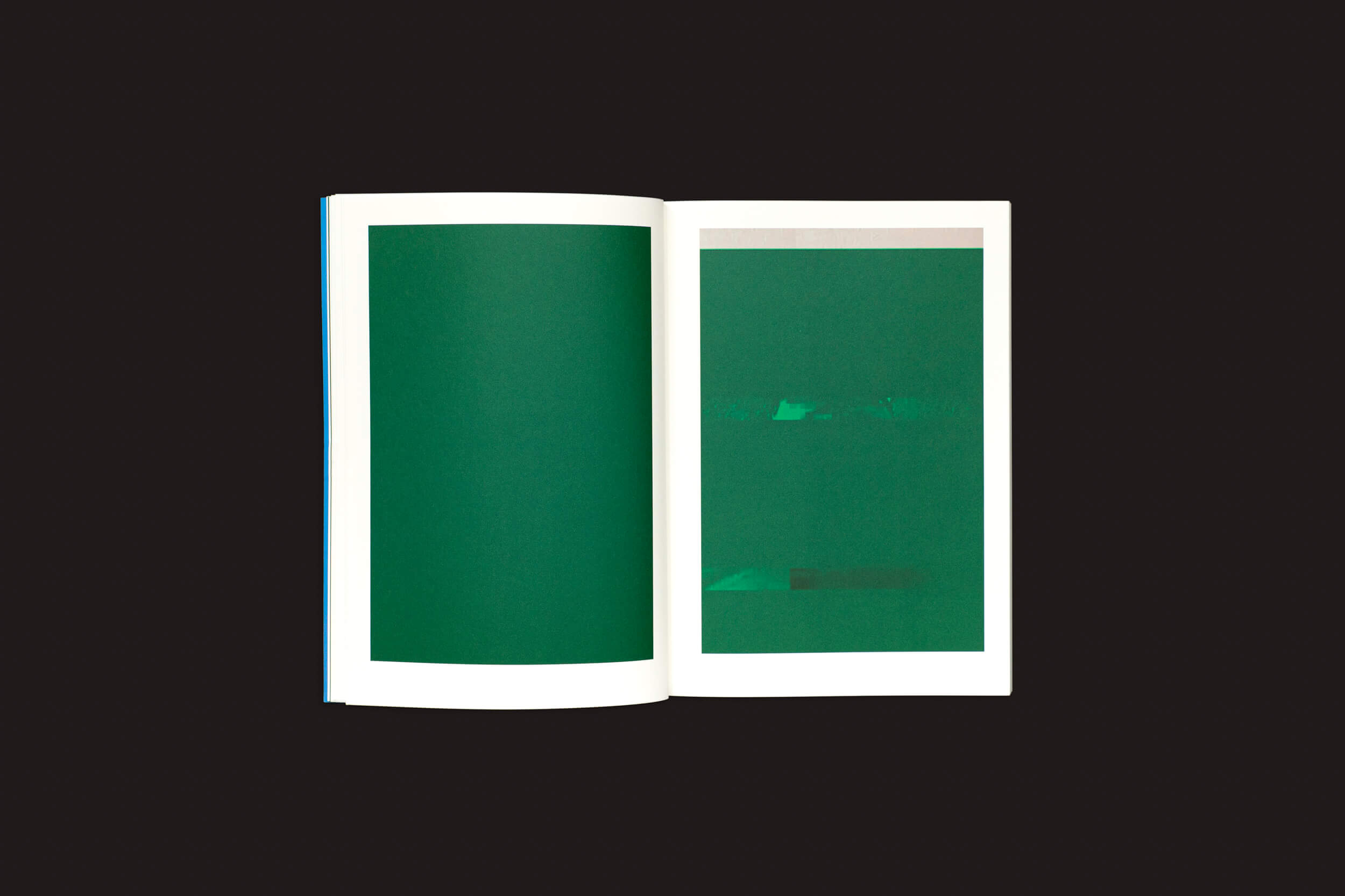 Um livro aberto contra um fundo escuro revela duas páginas com grandes retângulos verdes, um ligeiramente mais escuro. Este estilo abstrato reflete as interrupções e camadas em Taysir Batniji: Disruptions de Loose Joints.