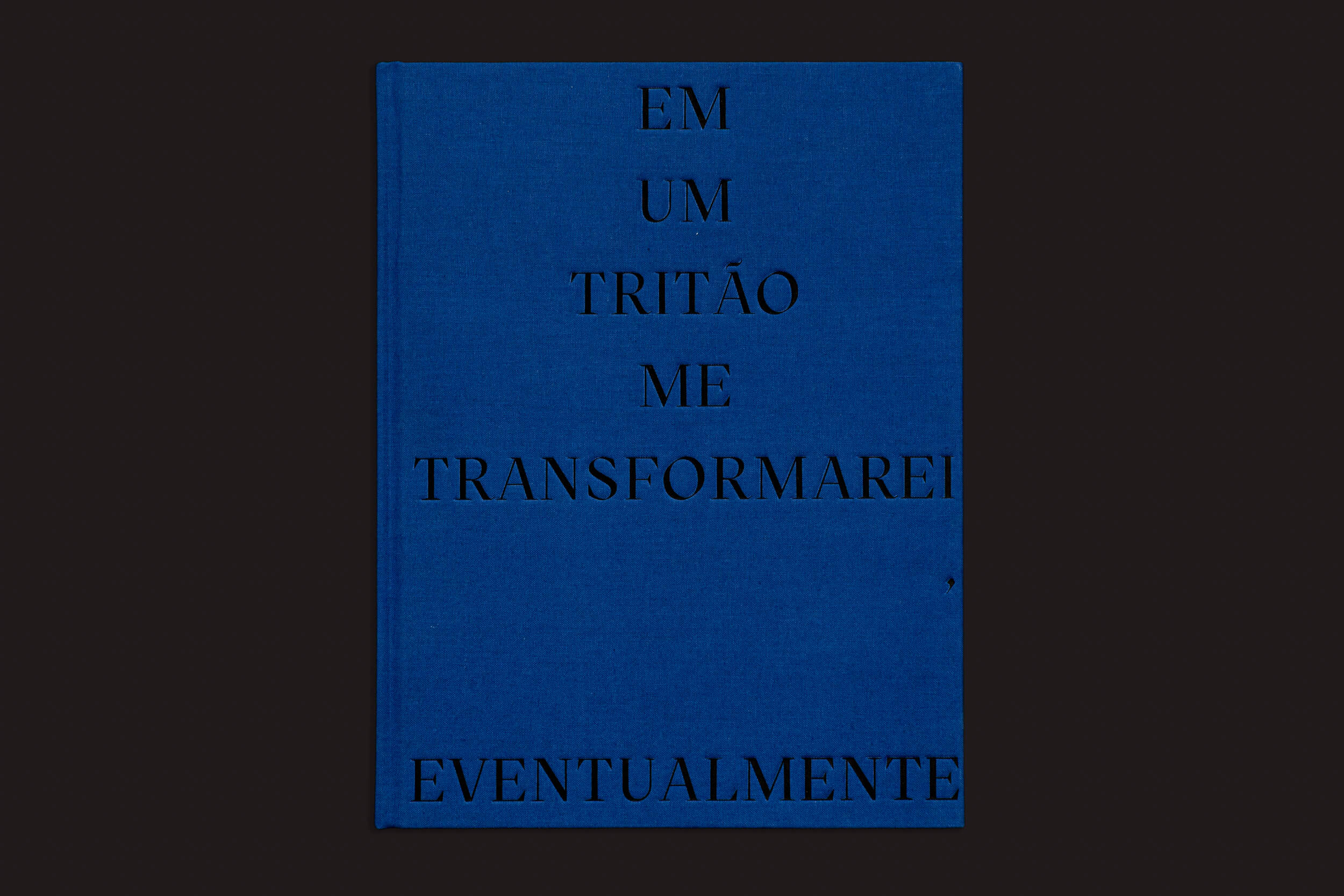 A capa azul do livro "Igor Morales: Em um Tritão me transformarei Eventualmente" da Editora Madalena apresenta texto em português preto, evocando emoção sobre um fundo liso e escuro.