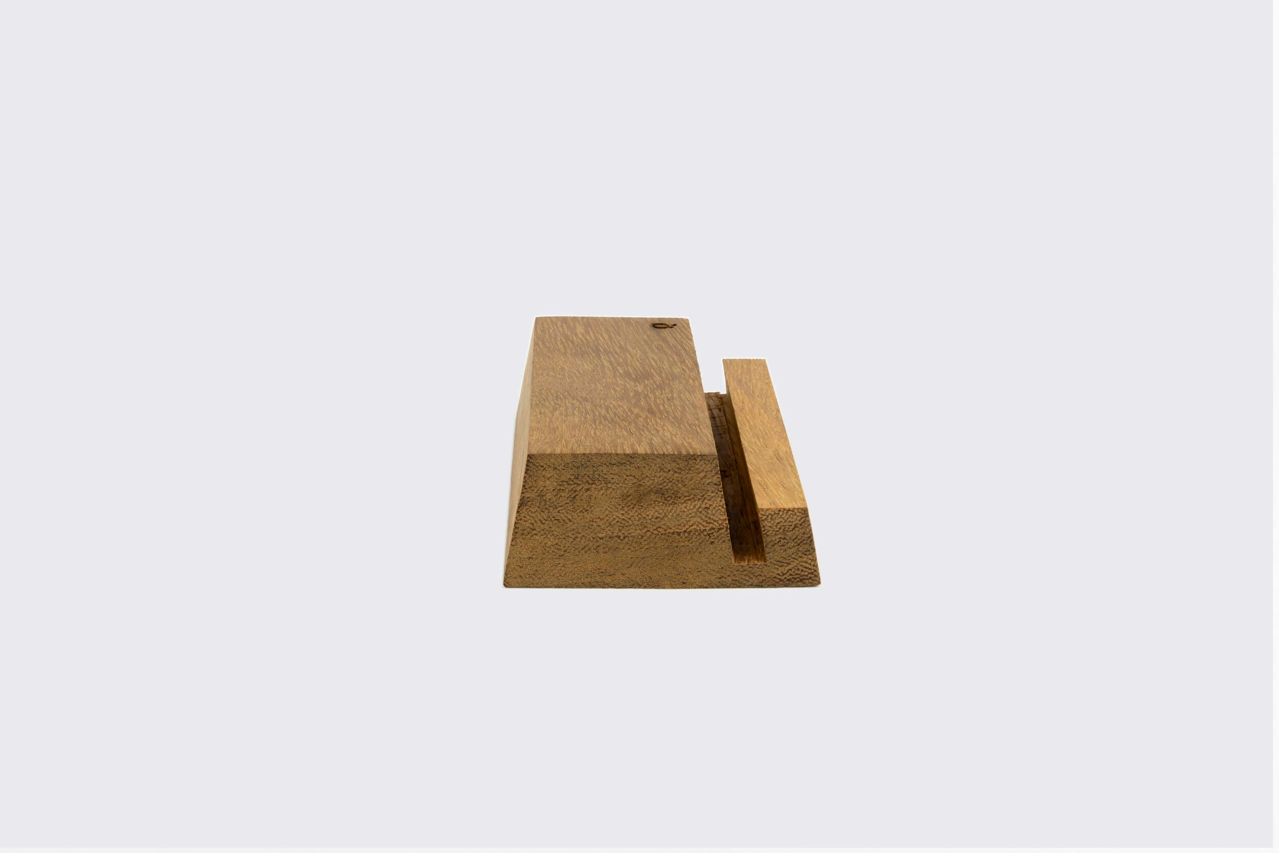 Um Display LP lindamente trabalhado por Goma Gringa, apresentando um bloco de madeira inclinado com uma fenda vertical central, fica elegantemente em um fundo cinza simples. Esta peça de edição limitada é um testamento à excelência da produção artesanal.