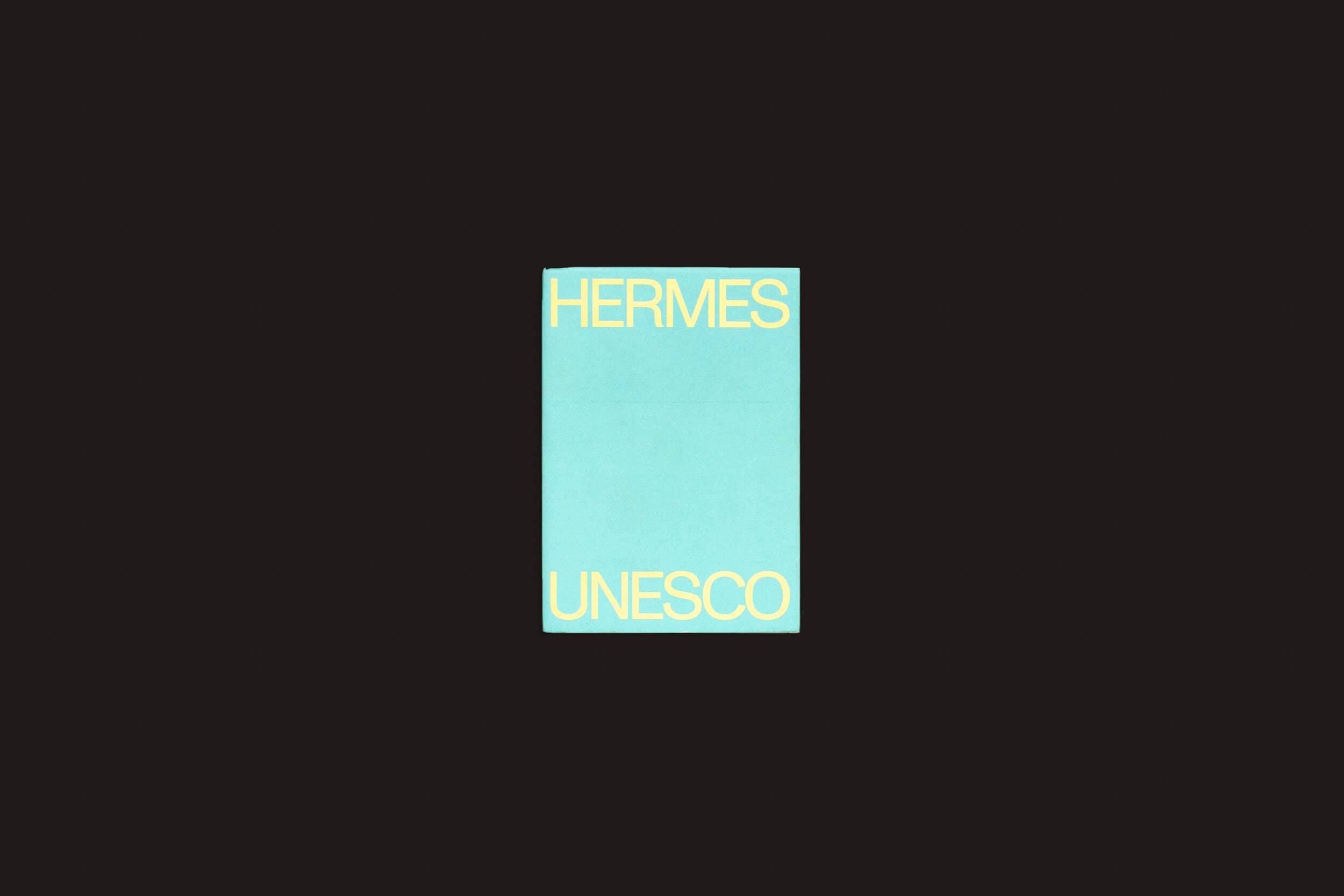 O livro Martín Bollati: Hermes/Unesco da SED Editorial, com sua capa turquesa, exibe HERMES na parte superior e UNESCO na parte inferior em fonte amarela em negrito. Explore um mundo onde civilizações antigas se cruzam com descobertas arqueológicas modernas contra um impressionante fundo preto.