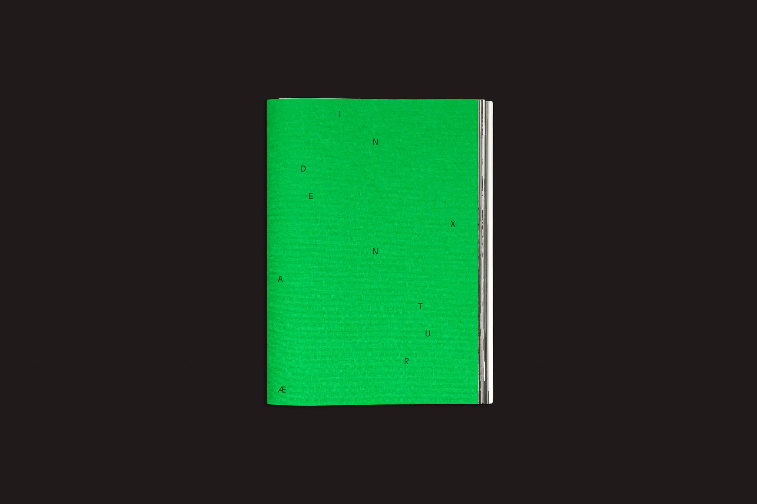 Um livro verde-esmeralda intitulado "Index Naturae: Vários Artistas", de Skinnerboox, com sua capa marcada por letras pretas espalhadas formando INDENTURÆ, está centralizado em preto sólido — um impressionante livro de fotos da Fotografia Europea.