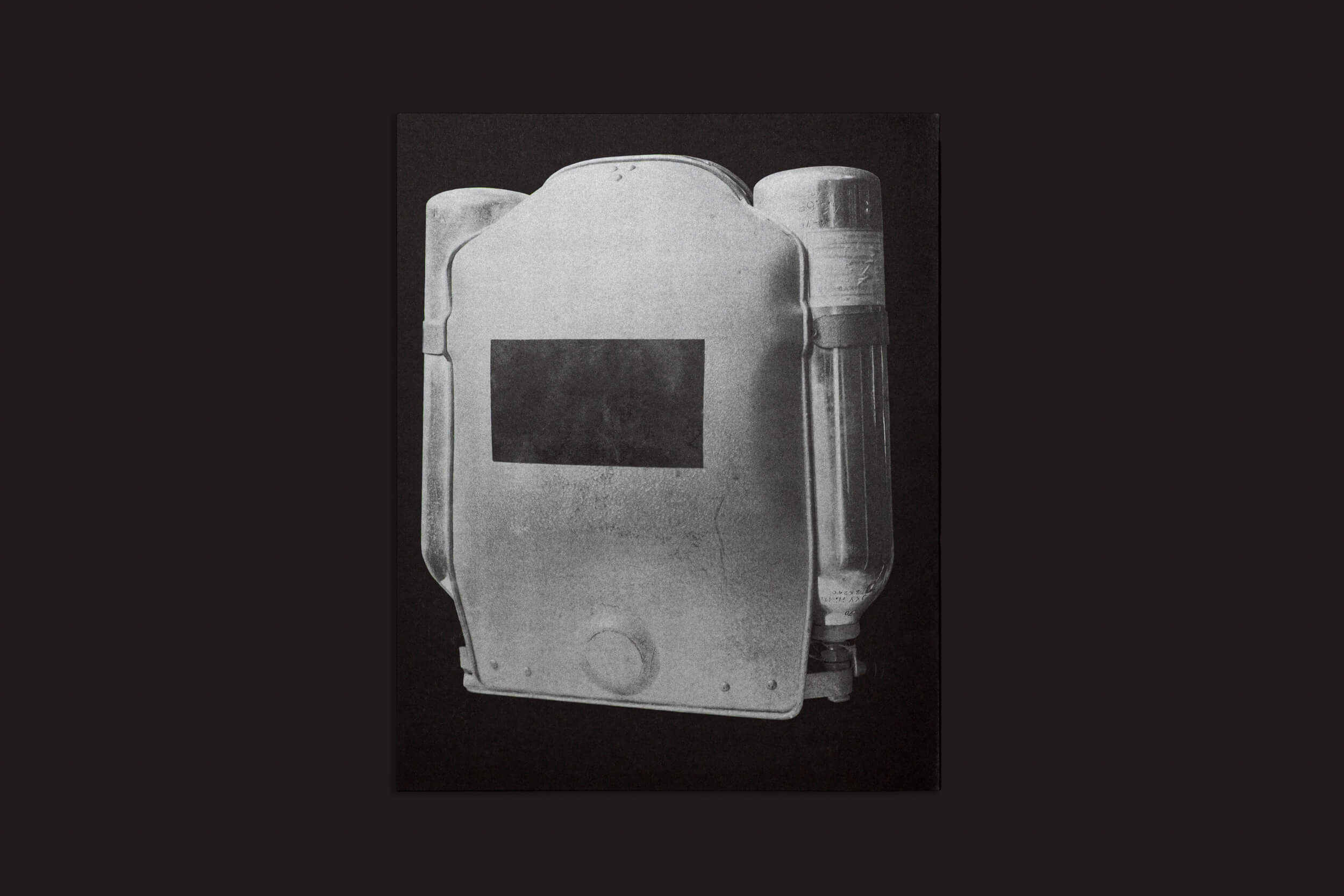 Ezio D'Agostino: O NEOS da Skinnerboox apresenta um jetpack vintage preto e branco de dois tanques contra um fundo escuro, com design minimalista com cilindros visíveis e um painel central, ecoando a tecnologia inicial da SpaceResources para mineração de asteroides.