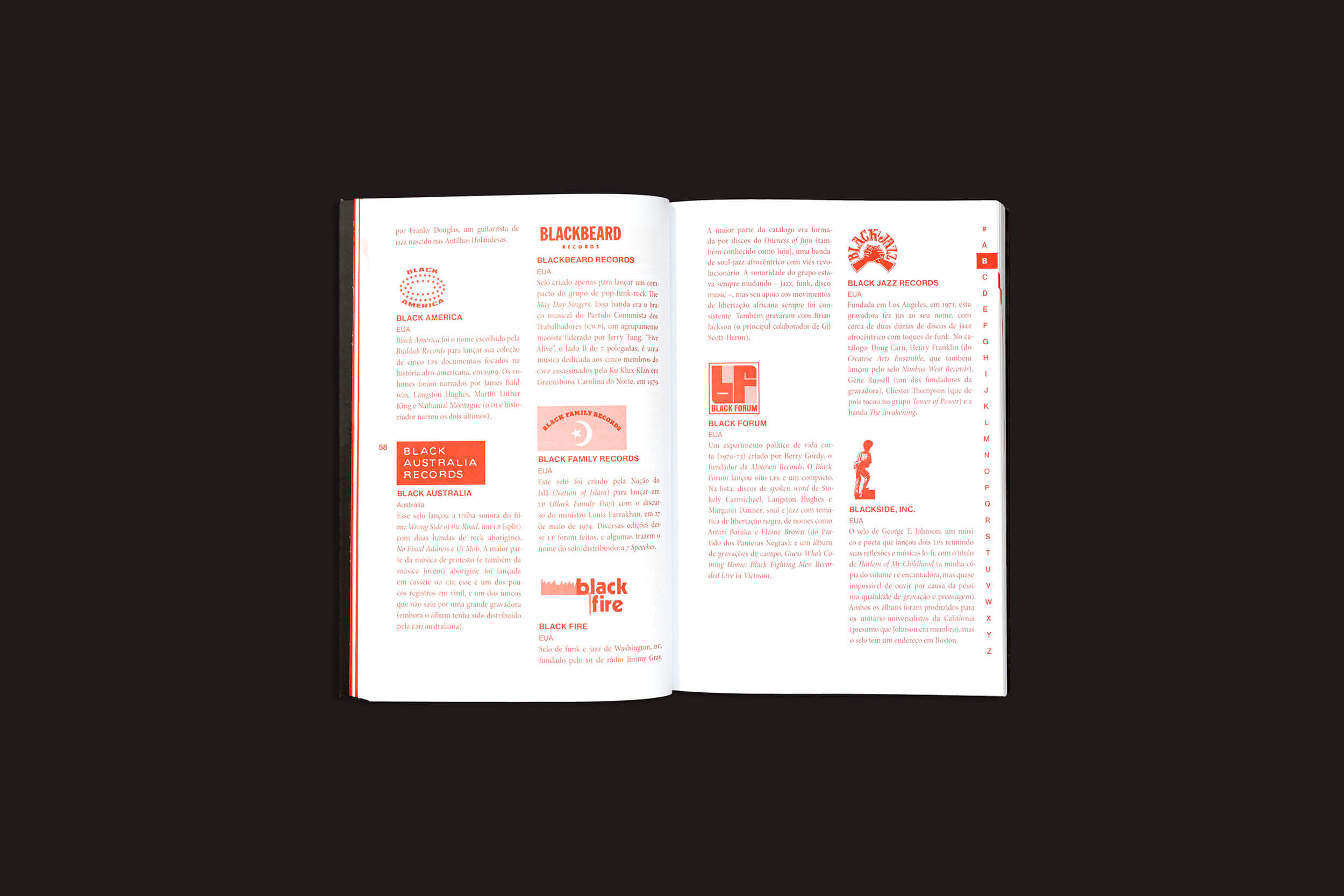 O livro *Josh MacPhee: Radical Records*, de sobinfluencia, está aberto sobre uma superfície escura, exibindo páginas cheias de texto e ilustrações vermelhas, como logotipos e silhuetas, acompanhadas de títulos vermelhos em negrito que lembram visuais dinâmicos vistos em capas de álbuns de música independente e coleções de discos de vinil.