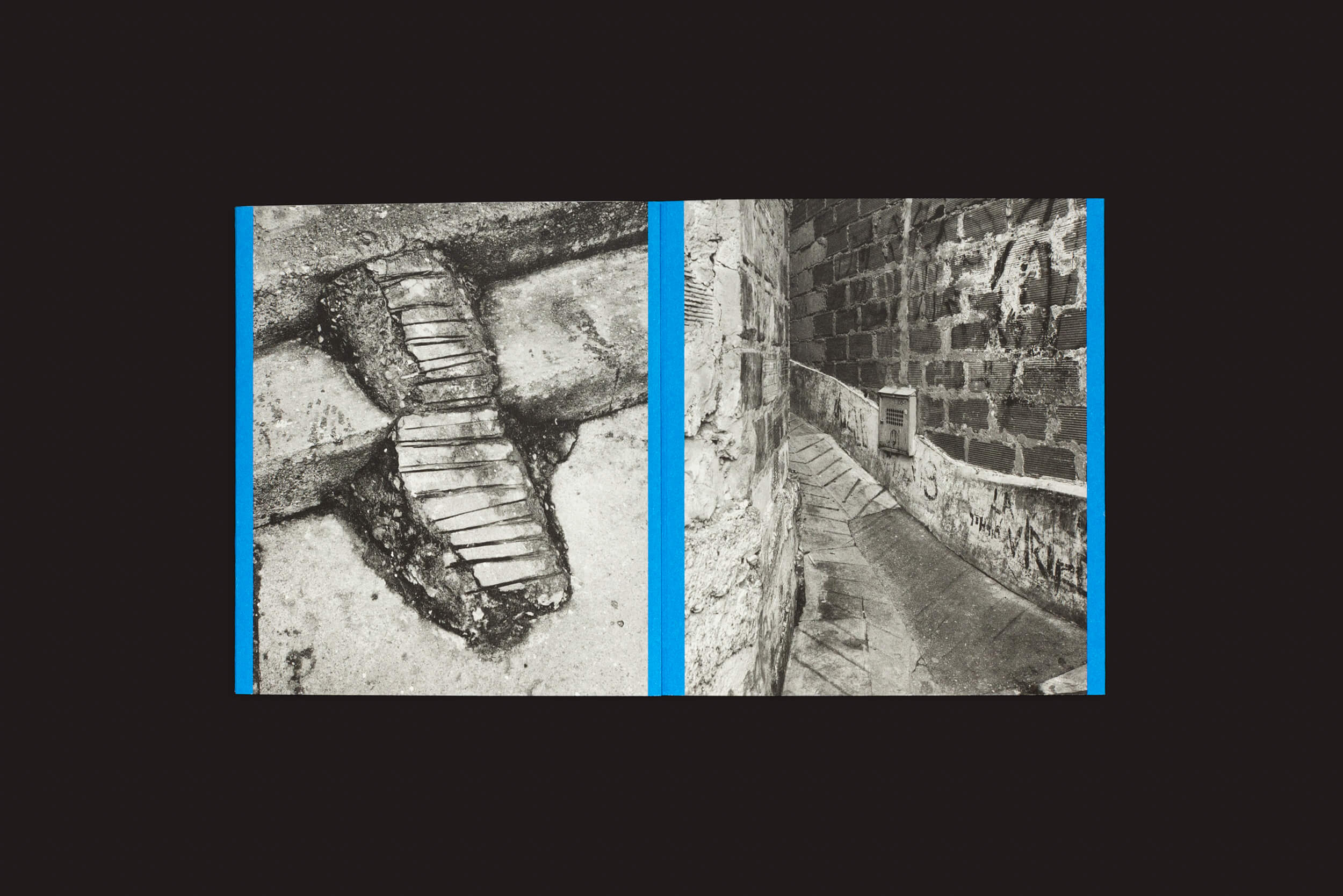 O lado esquerdo da imagem em preto e branco mostra uma passarela de pedra danificada com linhas azuis como aquelas em Rampitas de Thomas Locke Hobbs, enquanto o lado direito revela um beco estreito terminando com paredes de pedra e uma pequena escada. Apresentado por The Eriskay Connection.