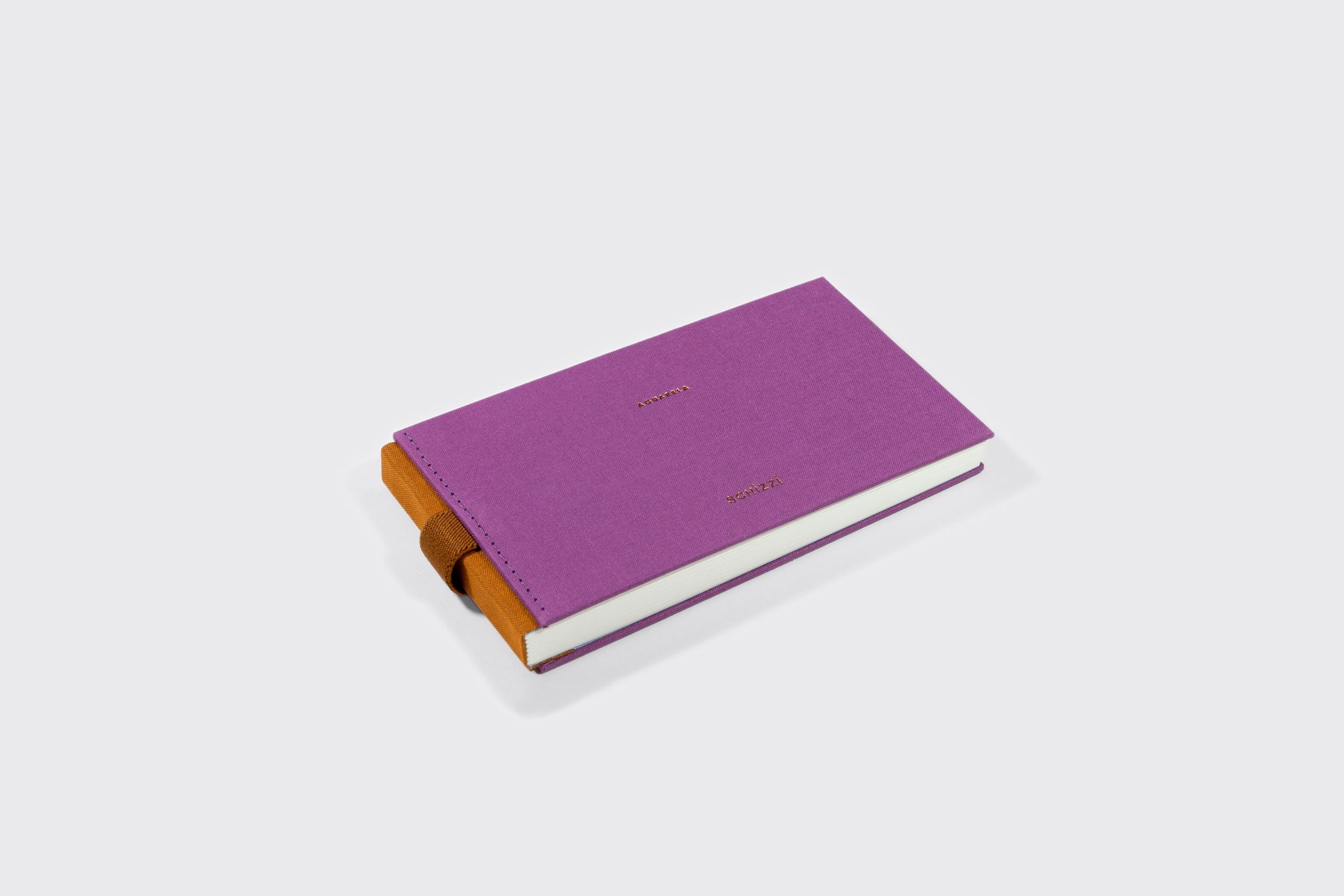 Um Caderno Aquarela Pocket roxo e fechado da Schizzibooks, com elástico marrom, sobre uma superfície branca. A capa tem um texto dourado simples e contém papel Marcate Cottage Premium em seu interior para aquarela.