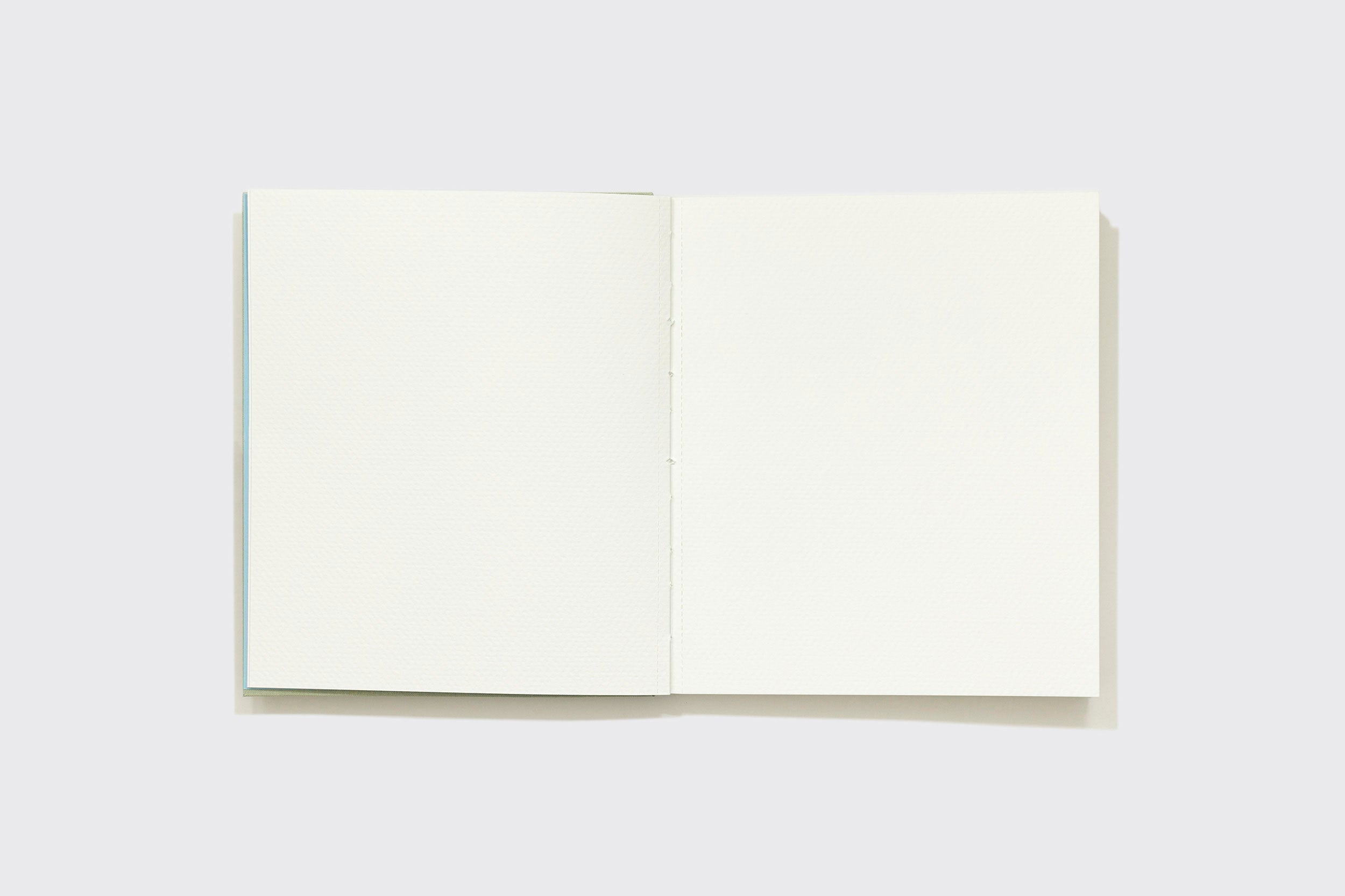 Um Caderno Aquarela da Schizzibooks, feito com páginas em branco de papel Marcate Cottage Premium, está centralizado em um fundo cinza claro e visto de cima.