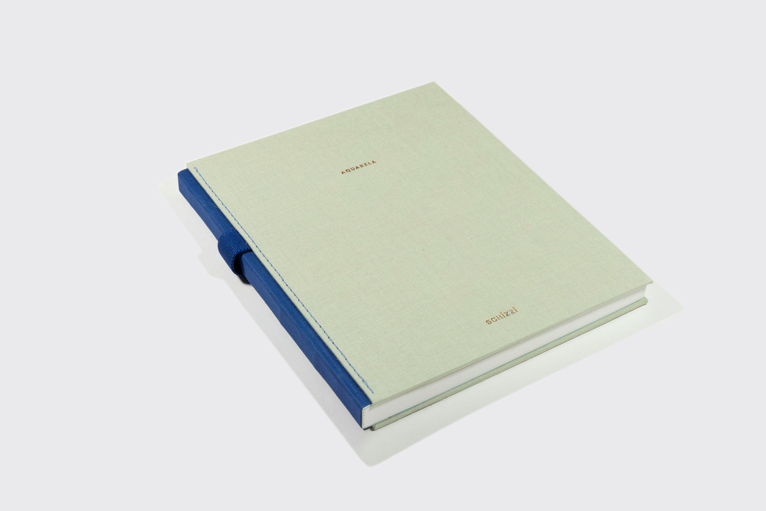 Um Caderno Aquarela de capa dura da Schizzibooks com capa cinza claro, lombada azul e texto dourado ARCHIVES GONZÁLEZ, feito de papel Marcate Cottage Premium, é mostrado em um fundo branco liso.