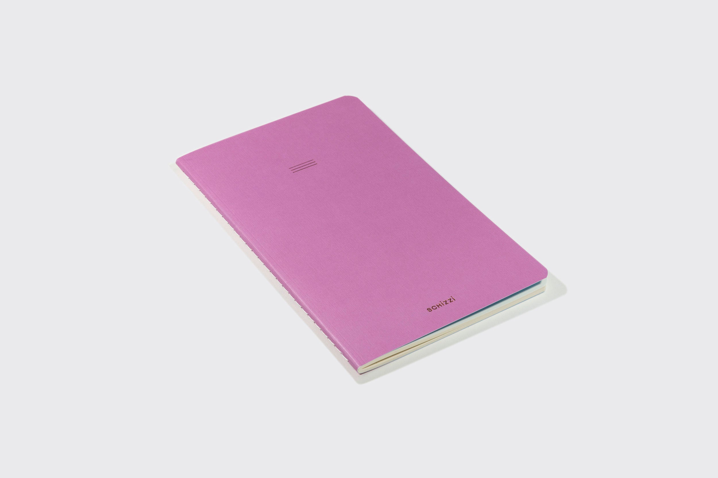 Um Caderno Flexível Schizzibooks de capa rosa lisa, cantos arredondados e inscrição "CONCEPT" dourado no canto inferior relacionado sobre uma superfície branca. Produzido no Brasil com papel livre de ácidos.