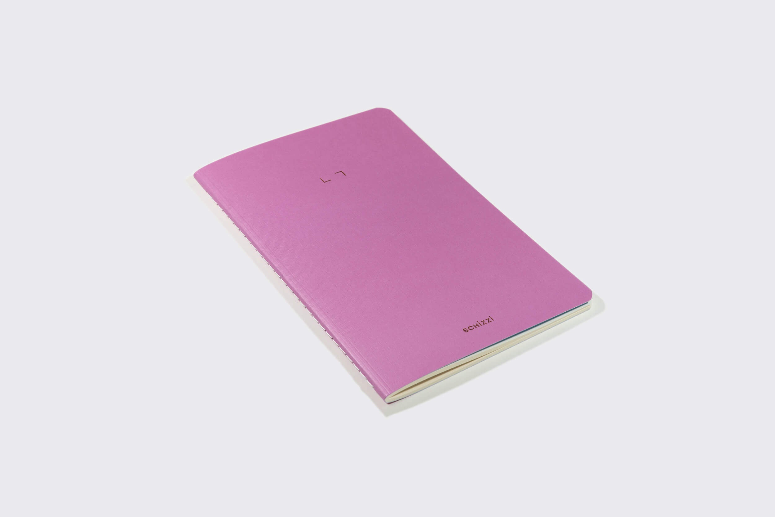 Um Caderno Flexível: Mirtilo rosa da Schizzibooks, produzido manualmente, repousa sobre fundo branco liso. Sua capa minimalista apresenta texto sutil destacando seu papel livre de ácidos para preservação da qualidade.