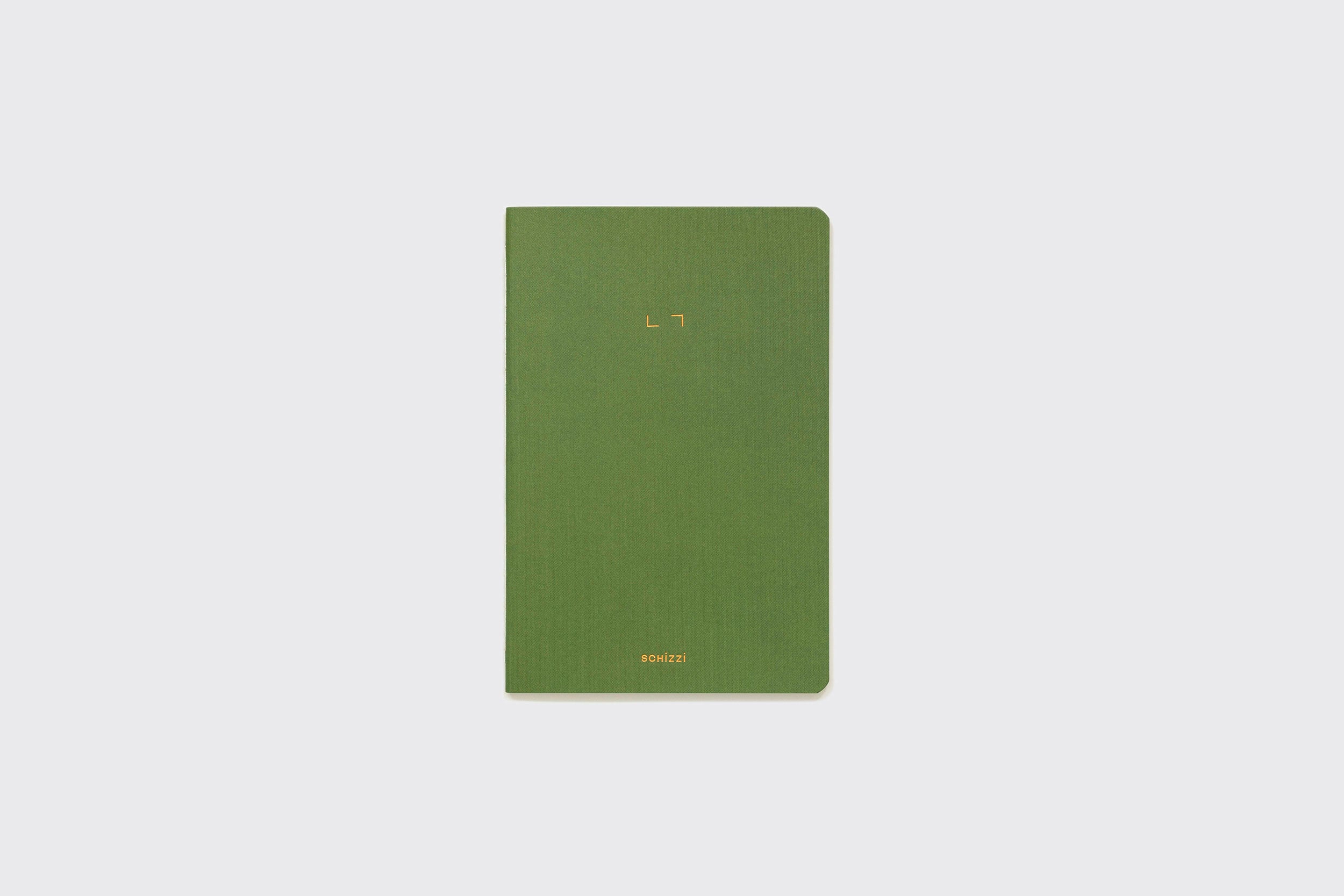 Um Caderno Flexível retangular verde da Schizzibooks, com cantos arredondados, está fechado sobre um fundo cinza claro liso. A capa apresenta um pequeno texto dourado no centro e na parte inferior, produzido manualmente no Brasil.