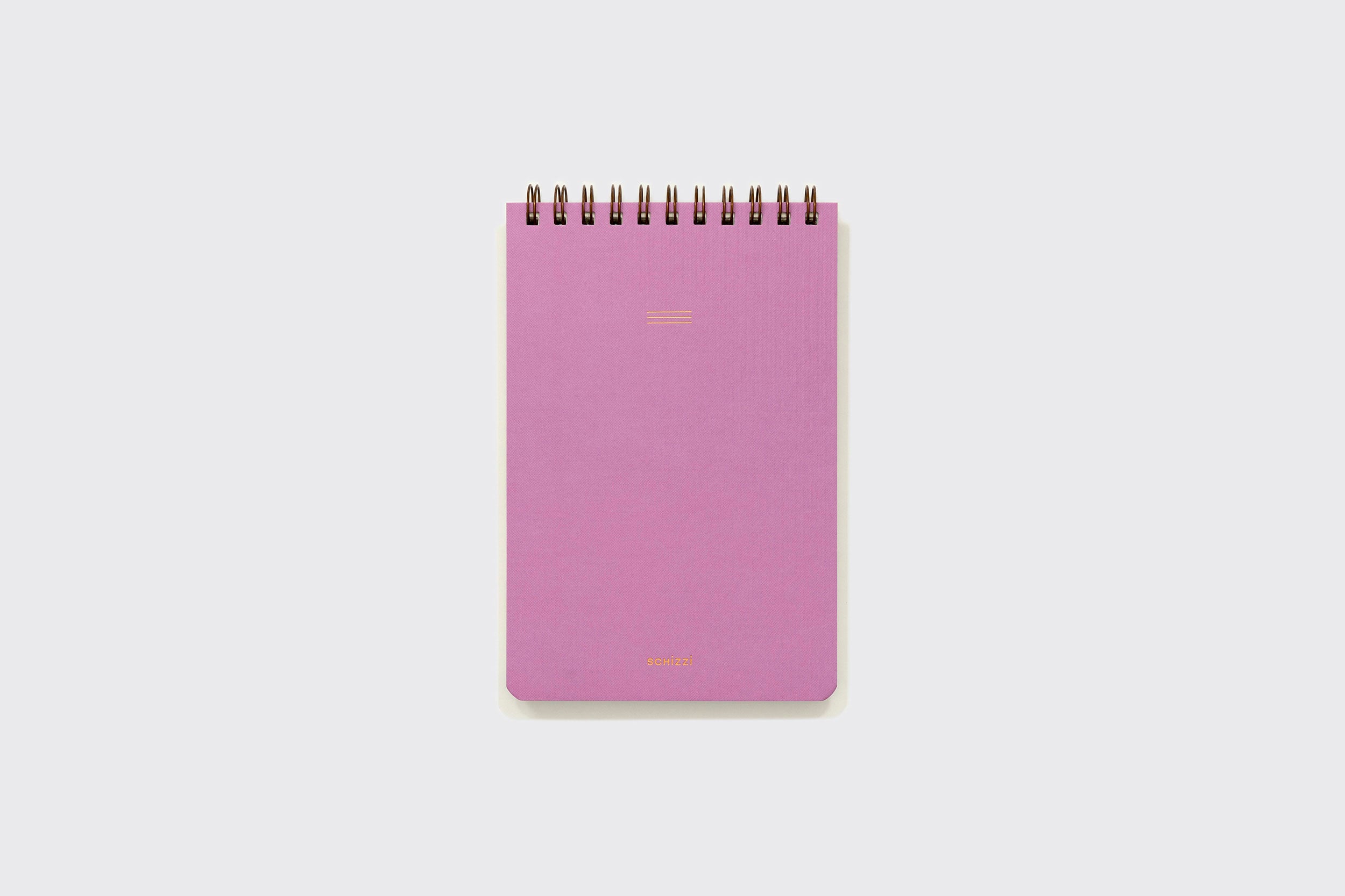 Um Caderno Reporter da Schizzibooks, com encadernação espiral rosa e cantos arredondados, está centralizado em um fundo cinza-claro liso. A capa em branco apresenta um texto dourado minimalista próximo à parte inferior. Fabricado no Brasil com papel pólen macio de alta qualidade.