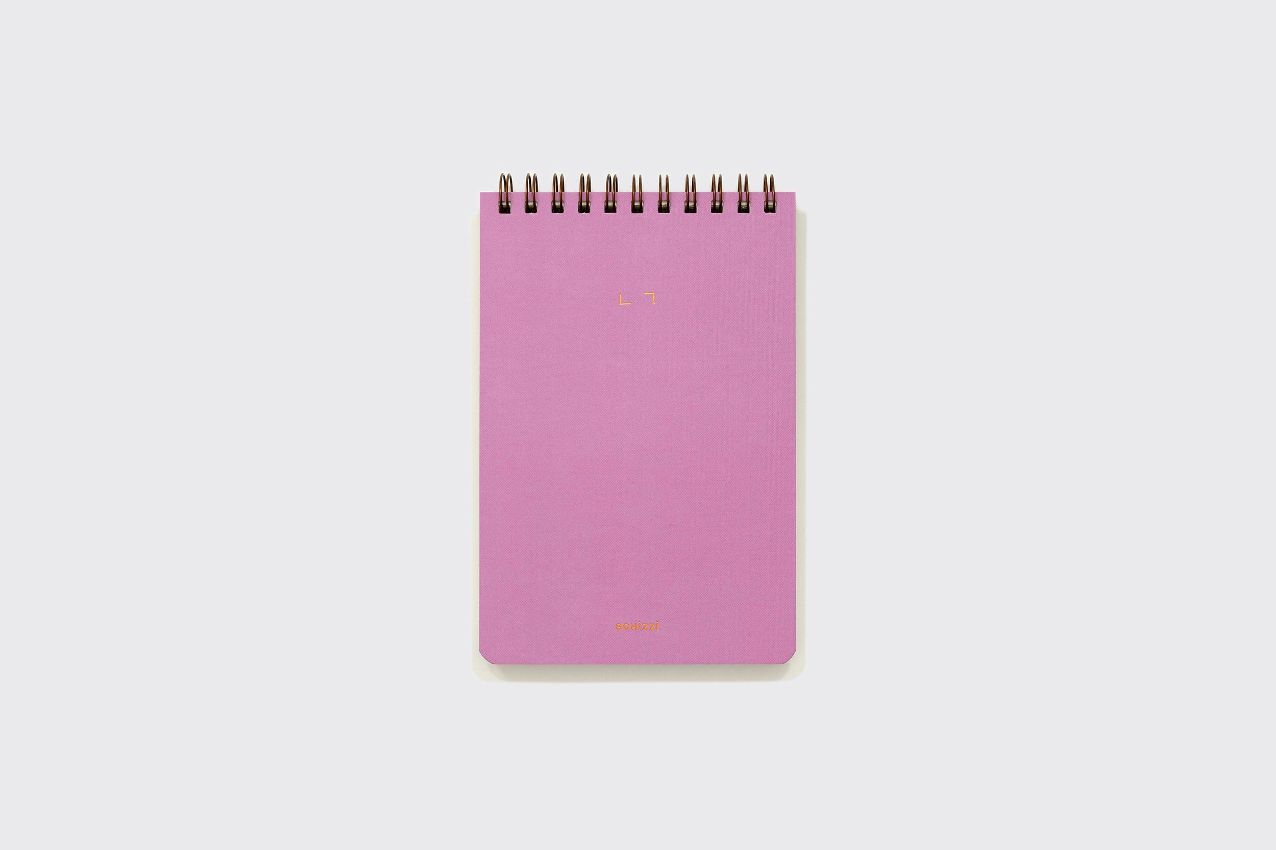 O Caderno Reporter da Schizzibooks é um caderno espiral rosa com capa lisa, feito no Brasil, mostrado verticalmente sobre um fundo cinza claro.