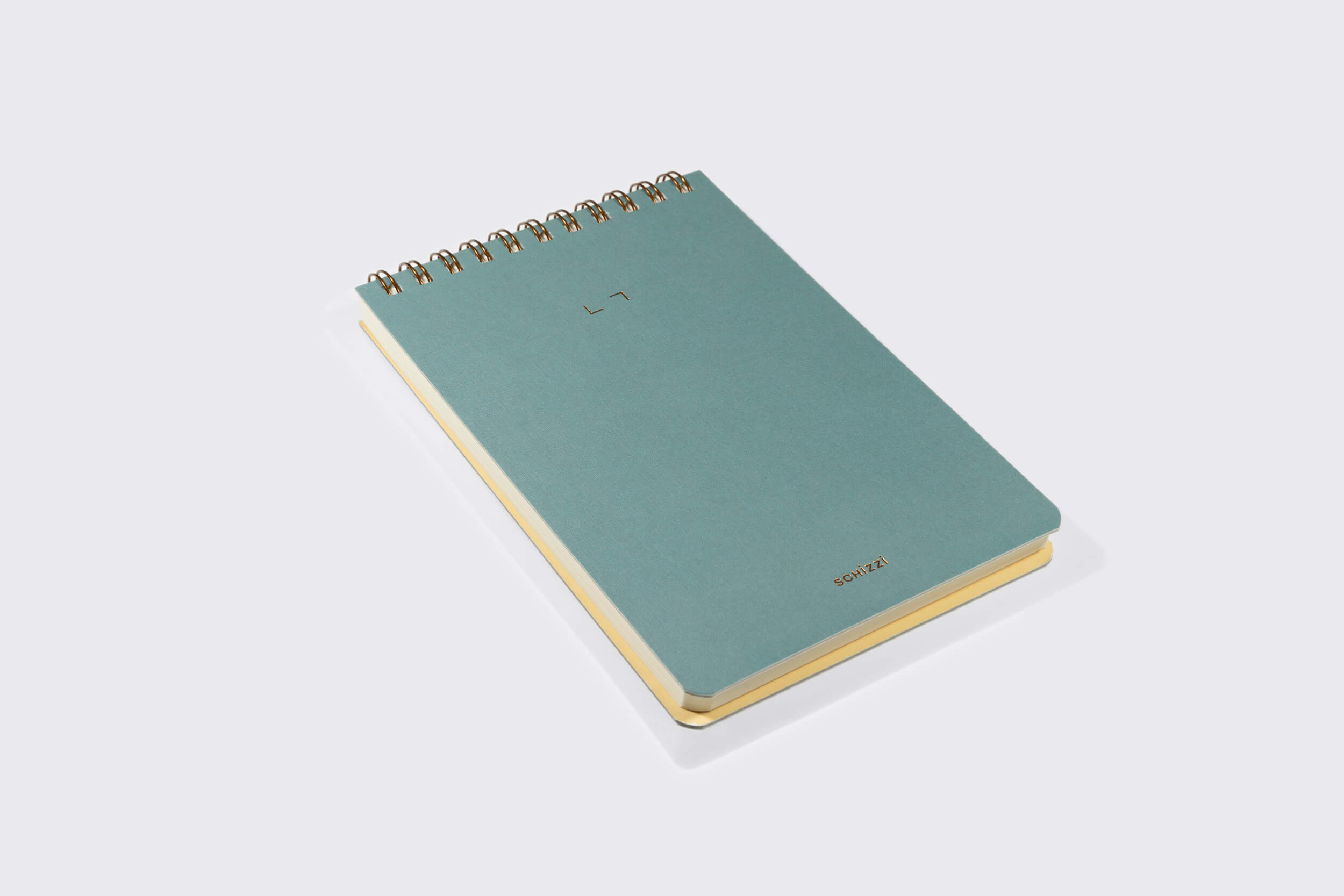 O Caderno Reporter: Nórdico da Schizzibooks, com seu design minimalista azul-esverdeado em espiral e encadernação wire-o bronze, repousa sobre uma superfície cinza. Sua capa apresenta um pequeno logotipo e "source" na parte inferior, enquanto as bordas das páginas revelam uma cor creme sutil semelhante ao papel pólen soft.