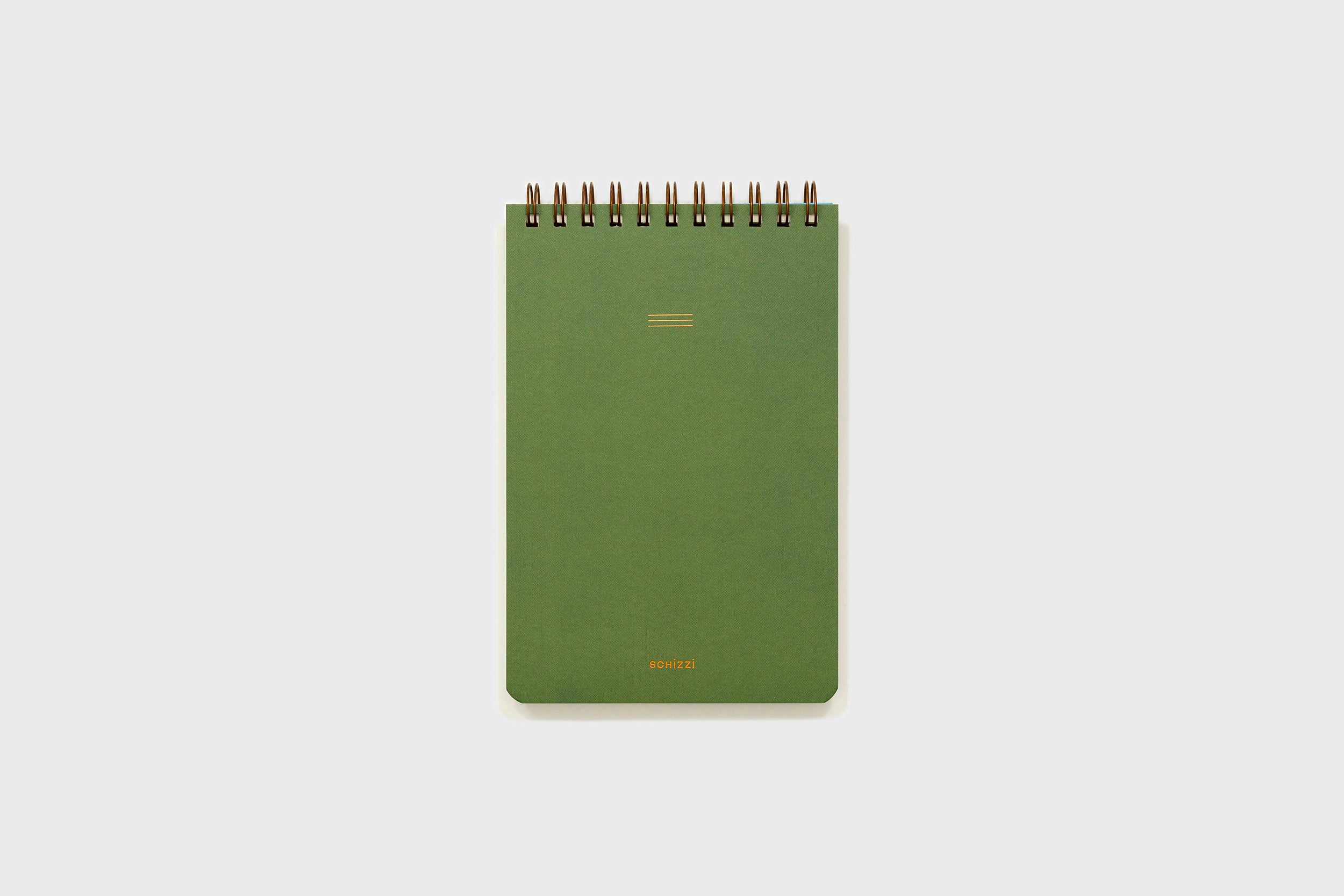 Caderno Reporter da Schizzibooks, verde, encadernado em espiral, com capa lisa, pequeno emblema dourado na parte superior e "BONDI" em dourado na parte inferior, feito à mão com papel sem ácido, sobre um fundo cinza claro.