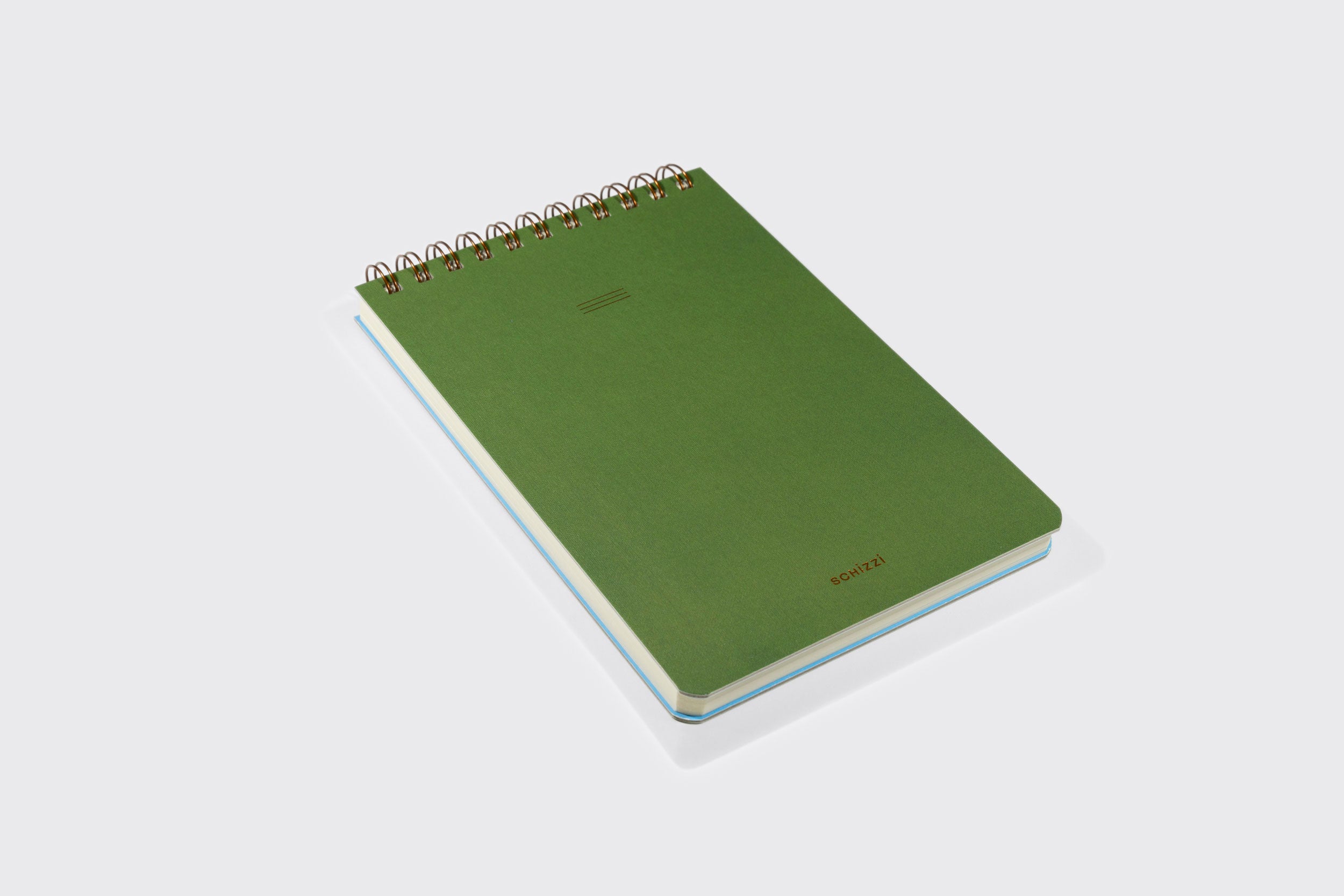 Caderno Reporter da Schizzibooks, verde, encadernado em espiral, com capa lisa e sem ácido, feito à mão e mostrado em ângulo sobre um fundo cinza claro. "SORTA" impresso em pequenas letras douradas no canto inferior direito da capa.