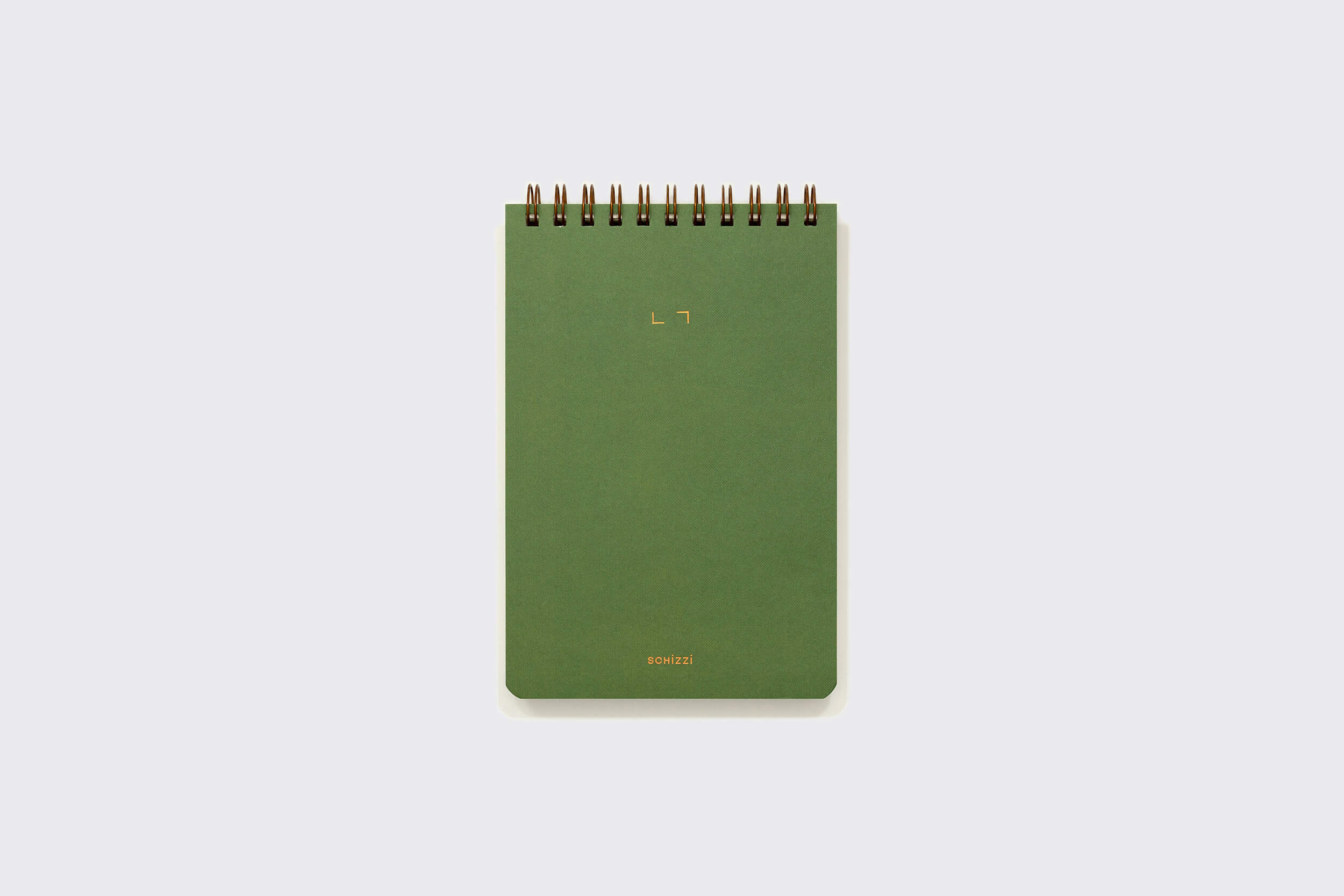 The Caderno Reporter: Oliva, da Schizzibooks, é um caderno espiral verde sobre um fundo cinza claro, com letras douradas minimalistas na capa e uma elegante encadernação wire-o em bronze.