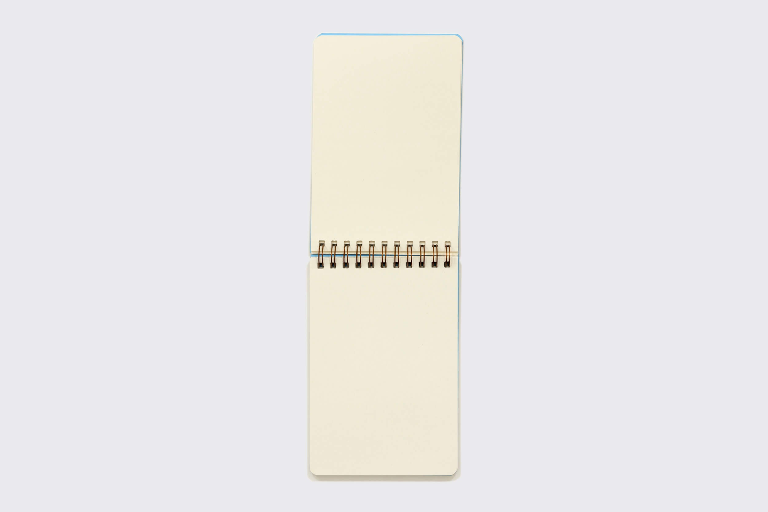 Um Caderno Reporter da Schizzibooks: O caderno Oliva com um wire-o bronze fica verticalmente sobre um fundo branco, exibindo suas páginas macias de papel pólen em branco e cor de creme. A capa aparece sutilmente no topo, sugerindo os tesouros dentro.