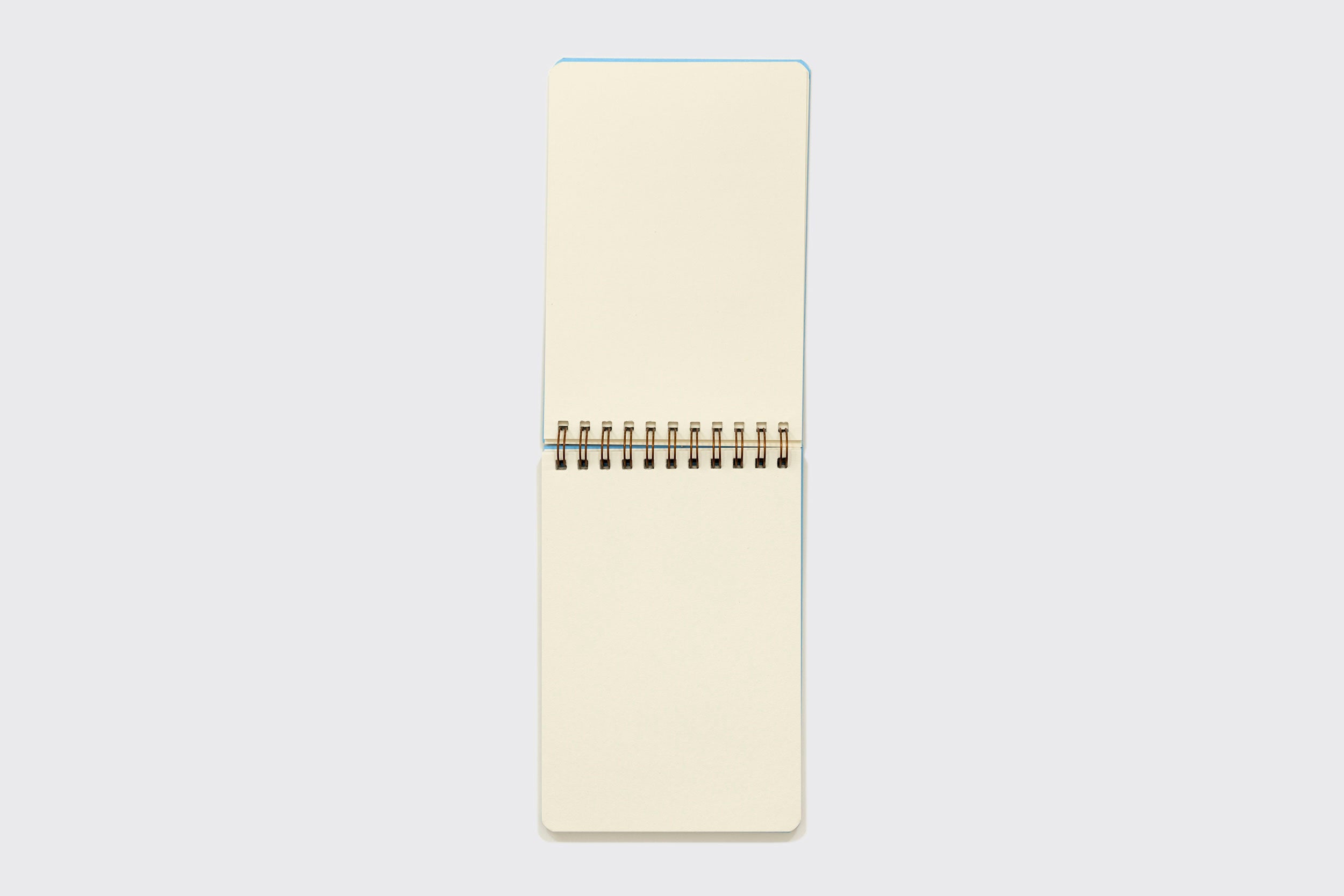 Um Caderno Reporter da Schizzibooks, feito à mão com papel livre de ácidos e páginas creme em branco, é aberto na vertical e centralizado sobre um fundo cinza claro.