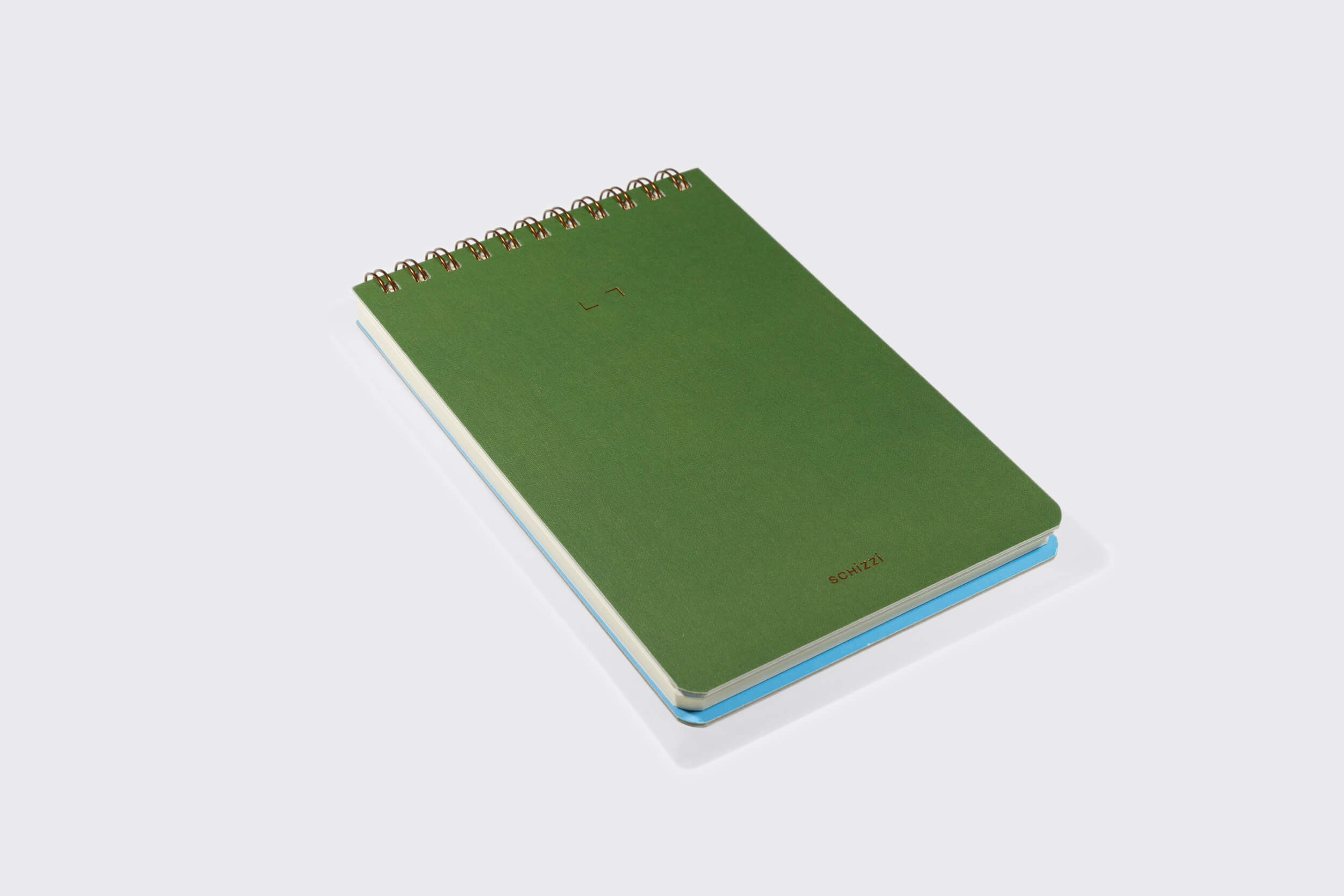 The Schizzibooks Caderno Reporter: Oliva, um caderno espiral verde minimalista, repousa sobre uma superfície branca. Ele ostenta um pequeno símbolo de sinal de mais e a palavra "falsificação" no canto inferior direito da capa, com elegante encadernação em bronze wire-o.