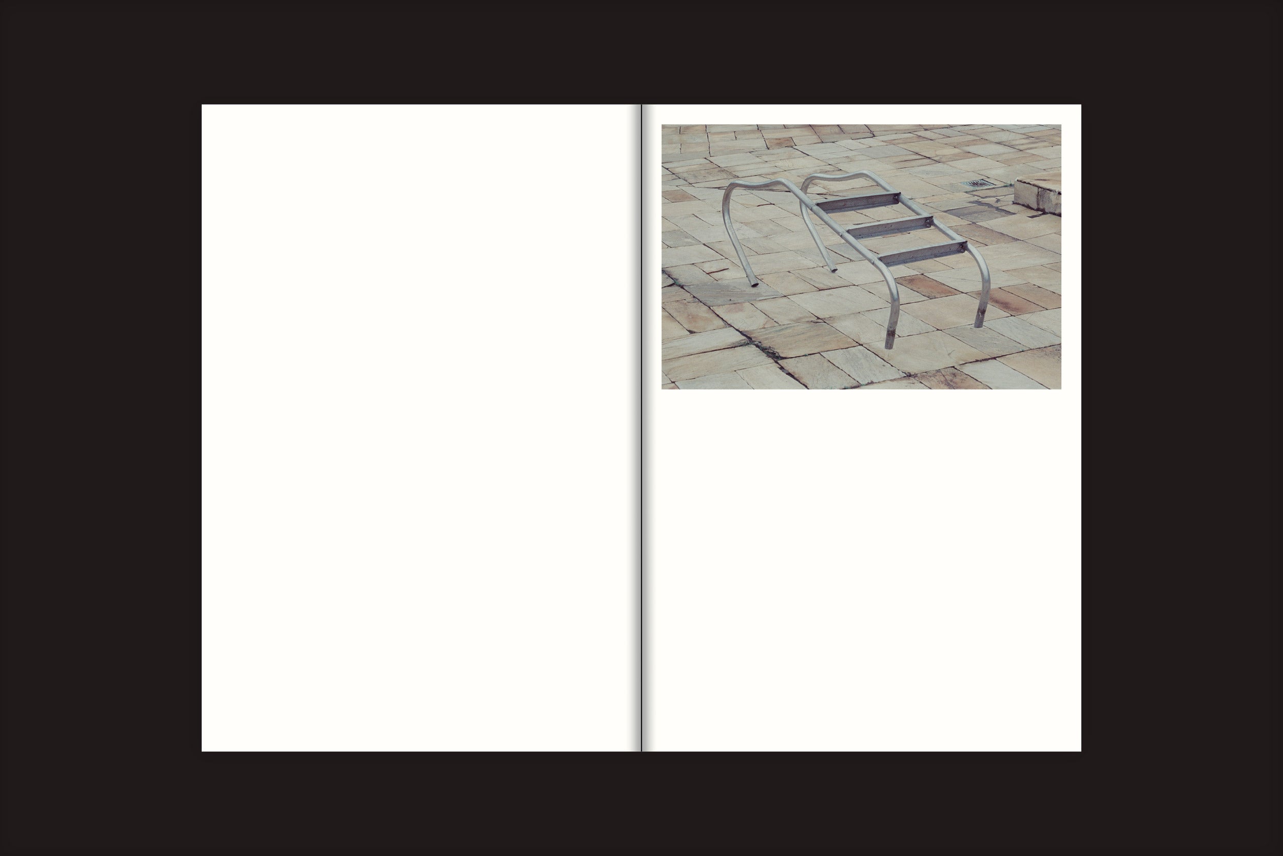 Uma página branca e vazia de duas páginas de "Tiago Lima: Nado", de Selo Turvo, apresenta uma pequena foto de uma estrutura de escalada de metal de um playground em um chão de azulejos no canto superior direito, emoldurada por uma ampla borda preta, evocando memórias do passado.