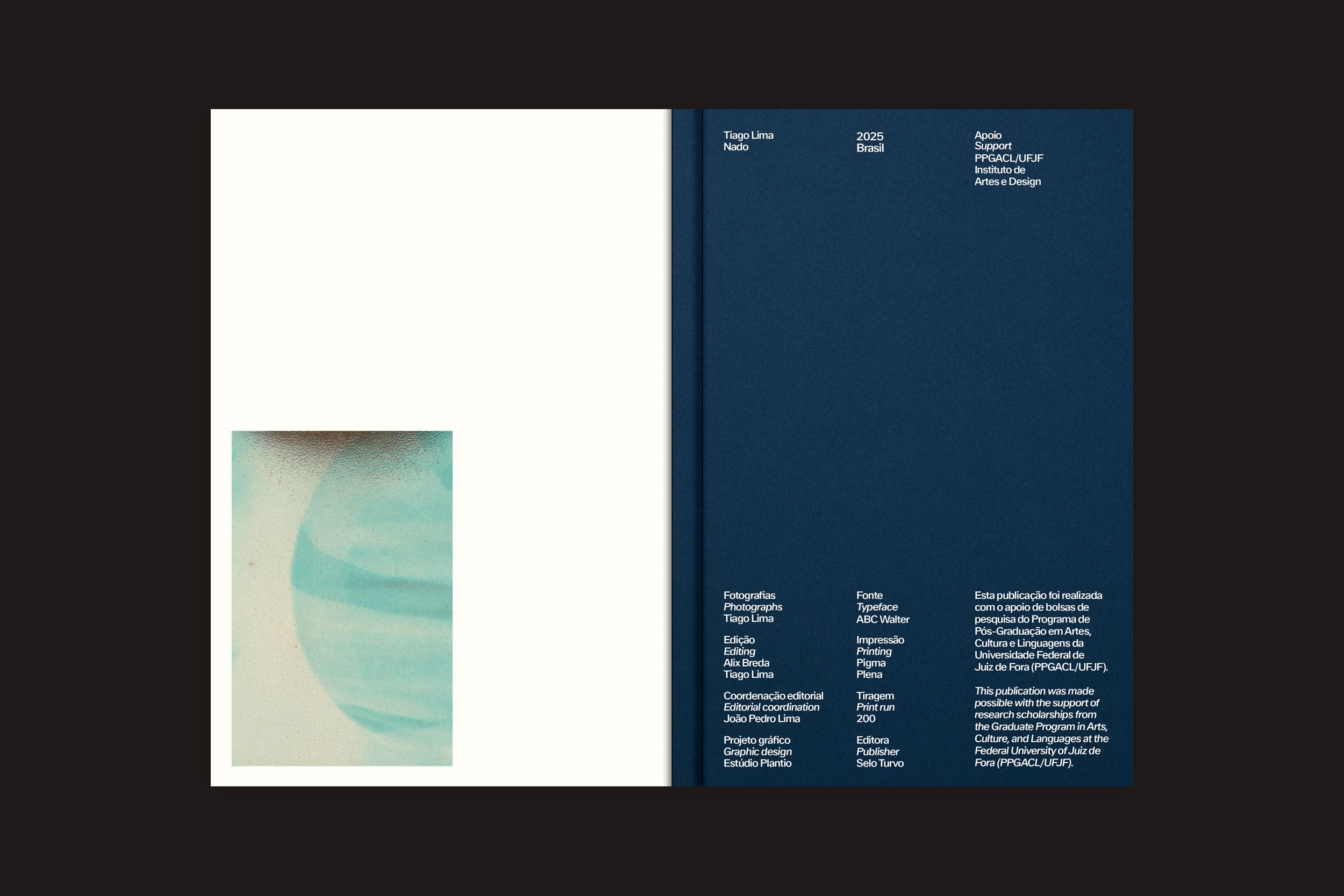 Uma cópia aberta de "Tiago Lima: Nado", do Selo Turvo, mostra um layout minimalista: a página da esquerda é branca com uma pequena imagem abstrata azul e bege semelhante a um planeta, enquanto a da direita é azul-escura com colunas brancas organizadas, típicas de uma brochura de 200 páginas.