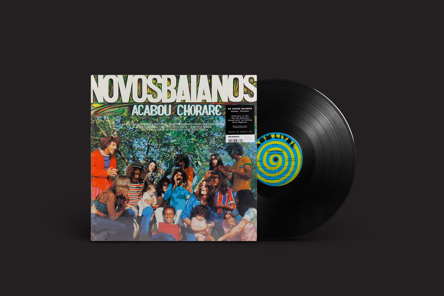 Um disco de vinil desliza parcialmente de sua capa, que apresenta Novos Baianos e o título do álbum "Acabou Chorare" em verde e branco. Lançado pelo Mr. Bongo, é uma imagem icônica que celebra o espírito alegre da música brasileira.