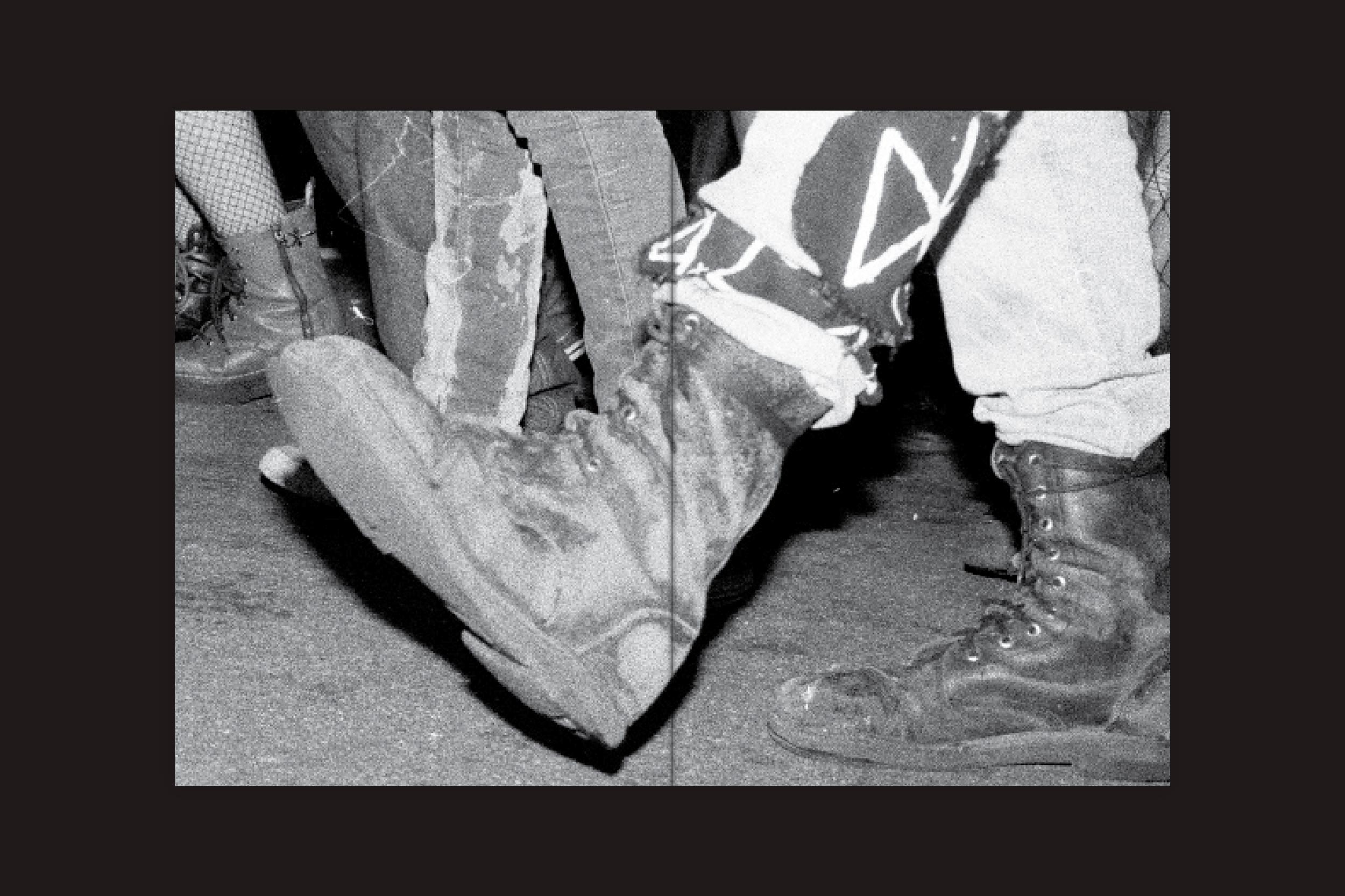 Foto em preto e branco de botas de combate desgastadas e calças rasgadas em um terreno arenoso evoca a energia punk, refletindo a existência fragmentada - arte da capa de "André Djanikian: Algunos sentimientos no cambian junto a las estaciones" do Selo Turvo.