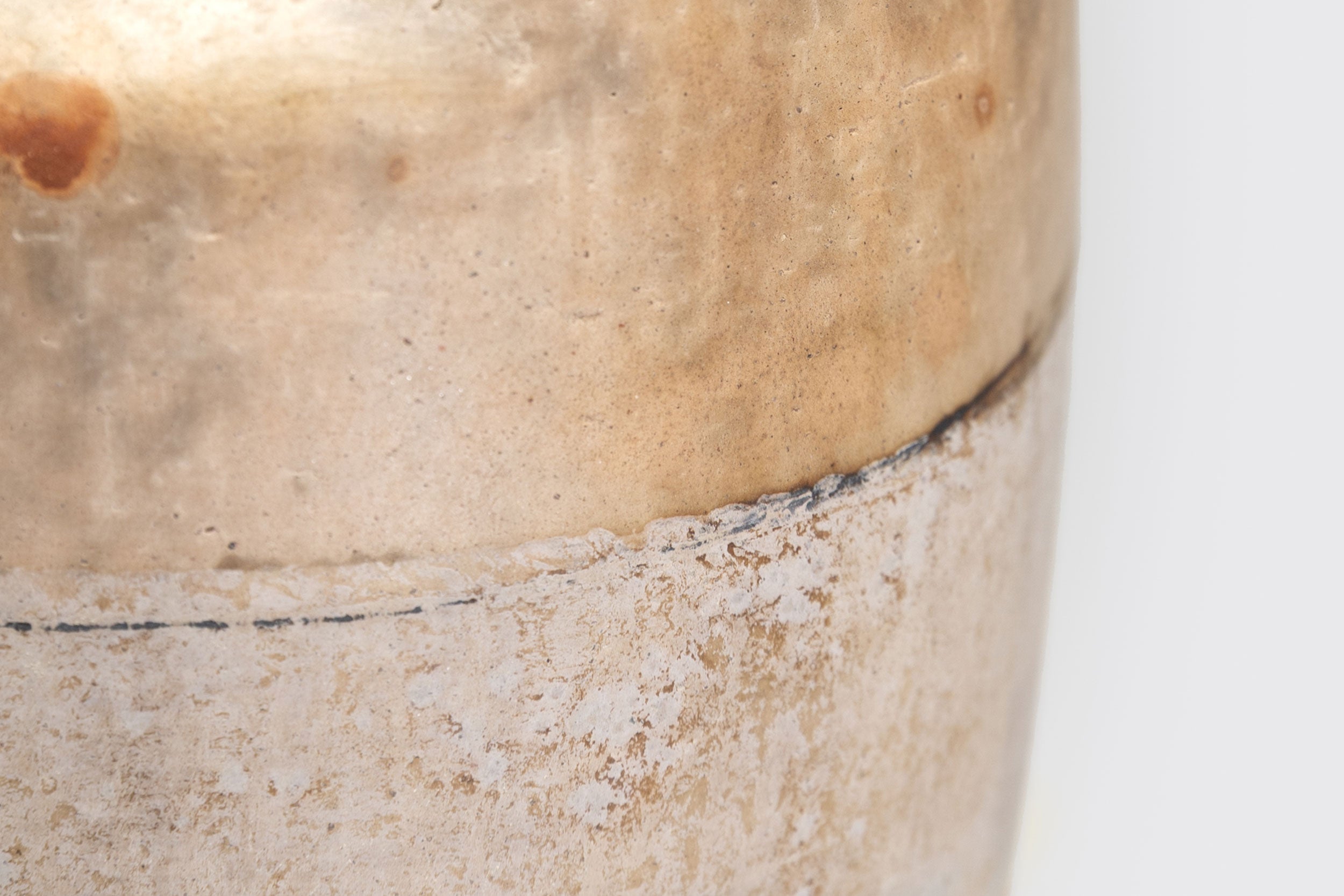 Close-up de Ânfora#1 de Derek Tasker-Norton, um vaso de cerâmica artesanal marrom claro envelhecido com textura áspera, costura visível e sutis variações de cor, exibido em um fundo branco liso.