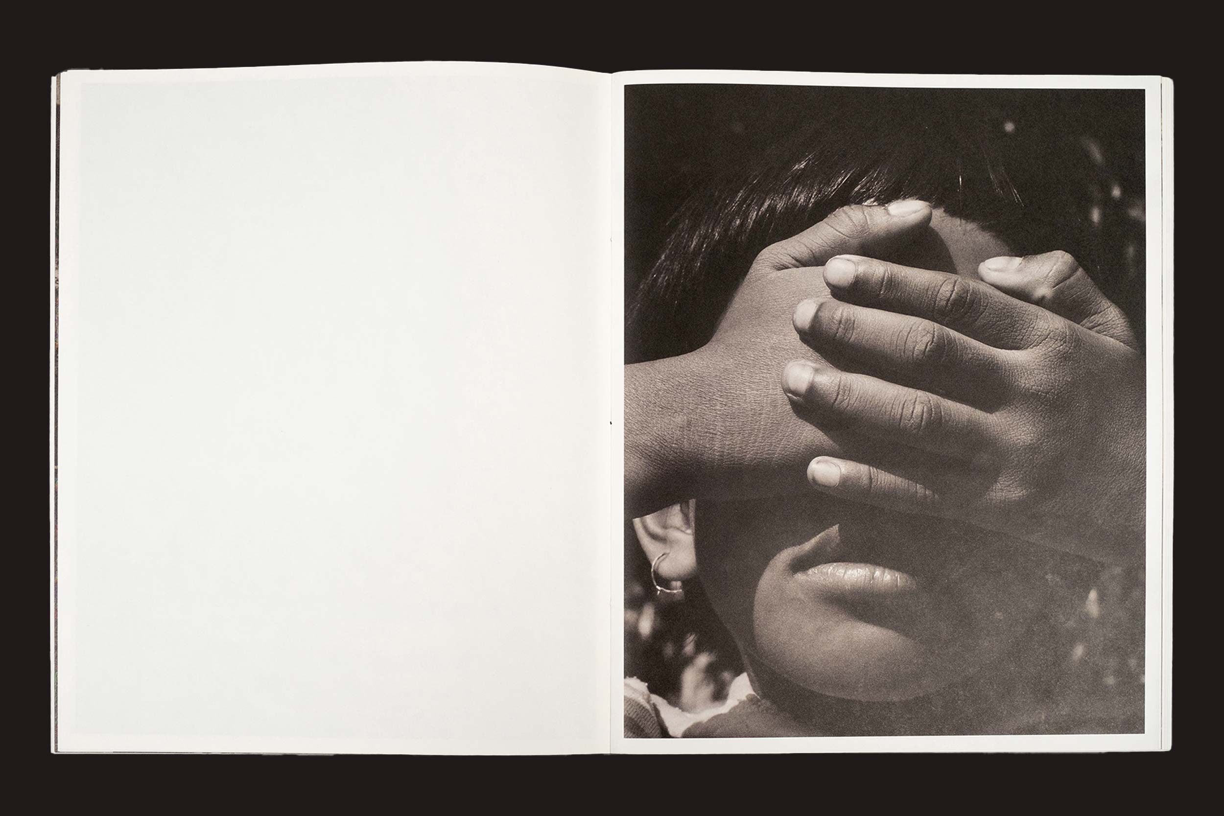 Uma cópia de "Bharat Sikka: Ripples in the Pond", da Fw:Books, está aberta; a página esquerda está em branco, enquanto a direita mostra uma fotografia em preto e branco de uma criança cobrindo os olhos com as duas mãos.