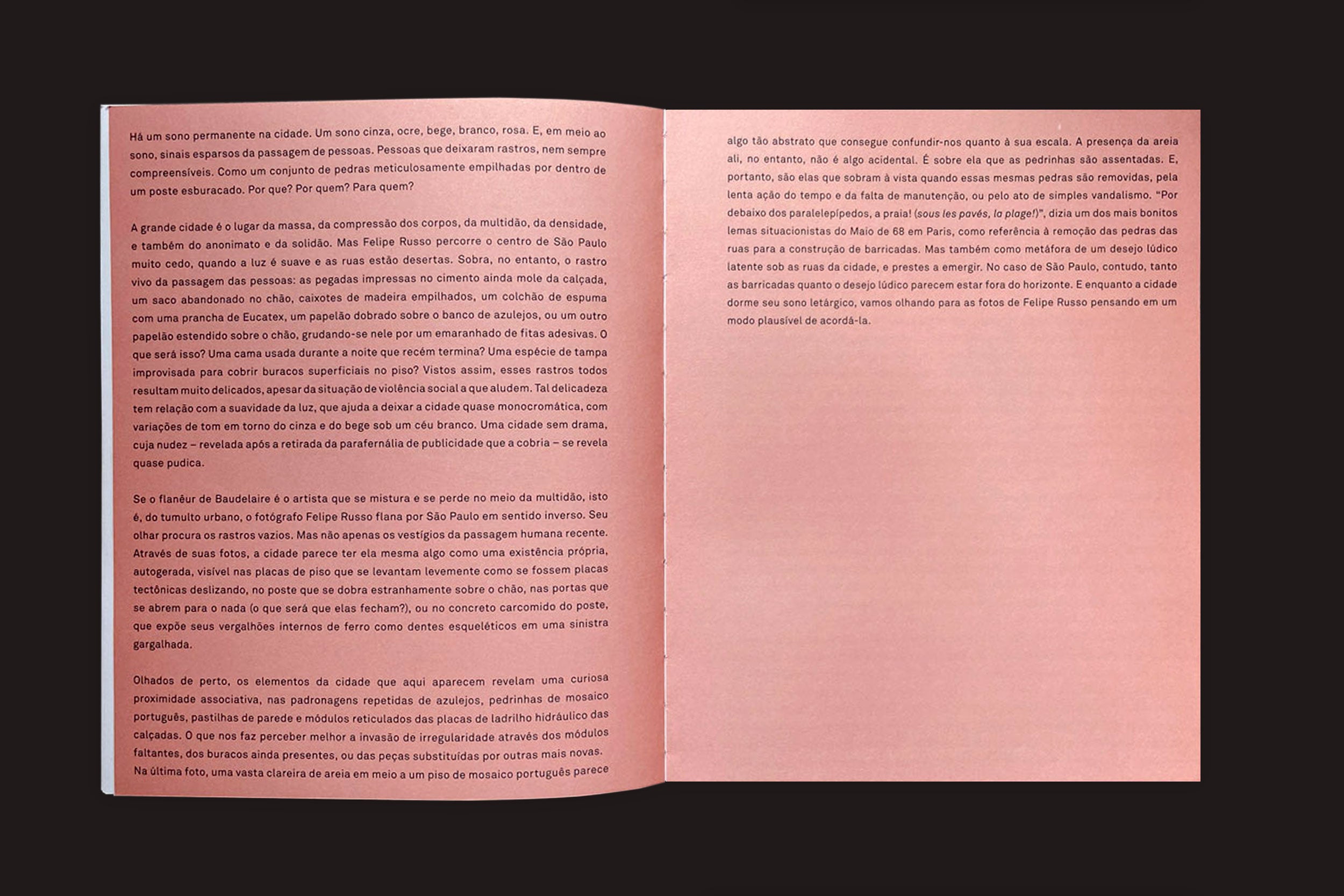Uma cópia de "Felipe Russo: Centro" da Auto-edição está aberto, revelando um texto em português densamente impresso em páginas rosadas contra um fundo escuro - ecoando cenas de fotografia urbana do centro de São Paulo.