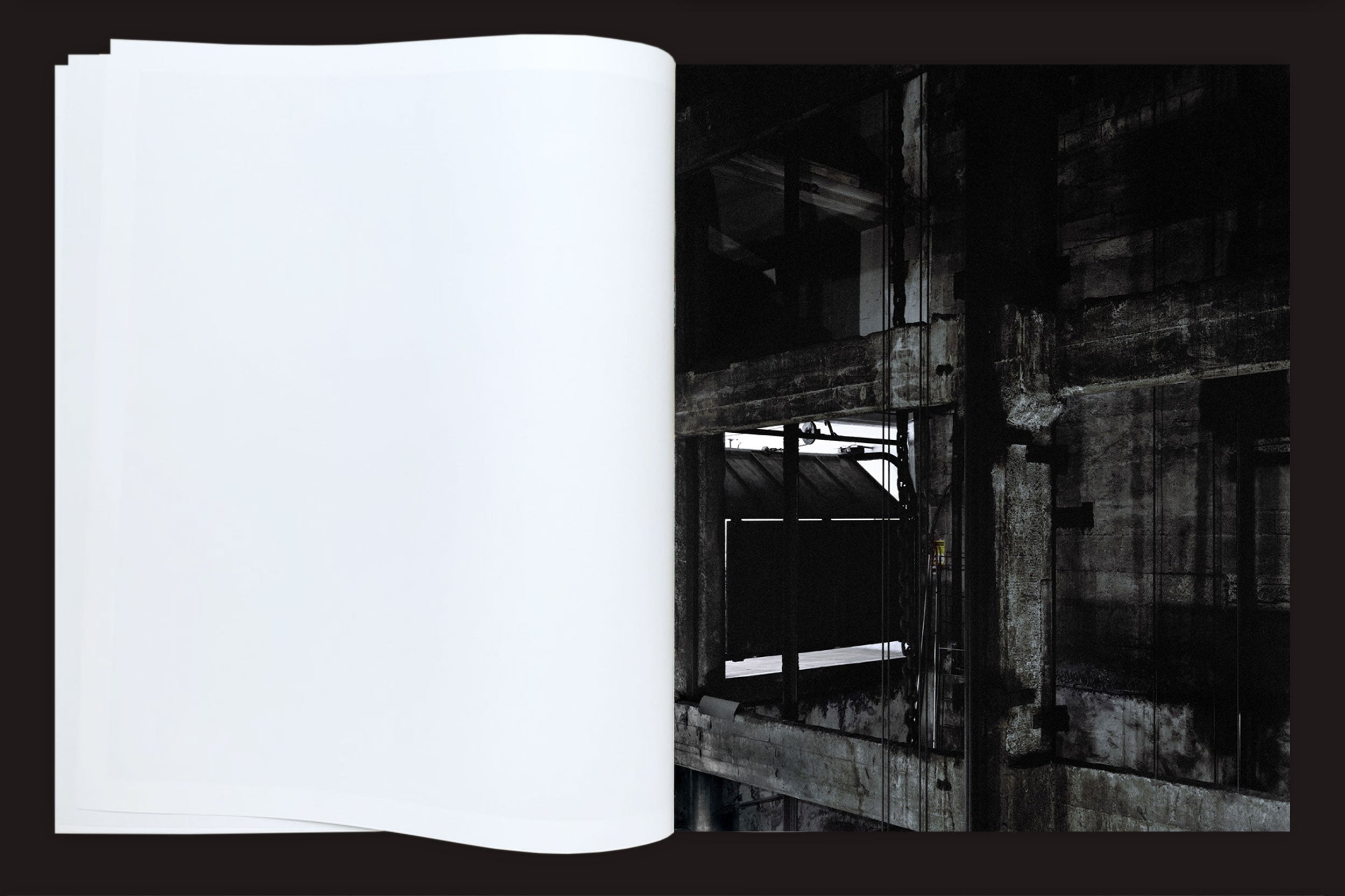 Felipe Russo: Garagem Automática by Auto-edição apresenta um livro aberto com uma página em branco à esquerda, em um cenário de interiores industriais de São Paulo - paredes e vigas de concreto que evocam a fotografia arquitetônica e a paisagem urbana.