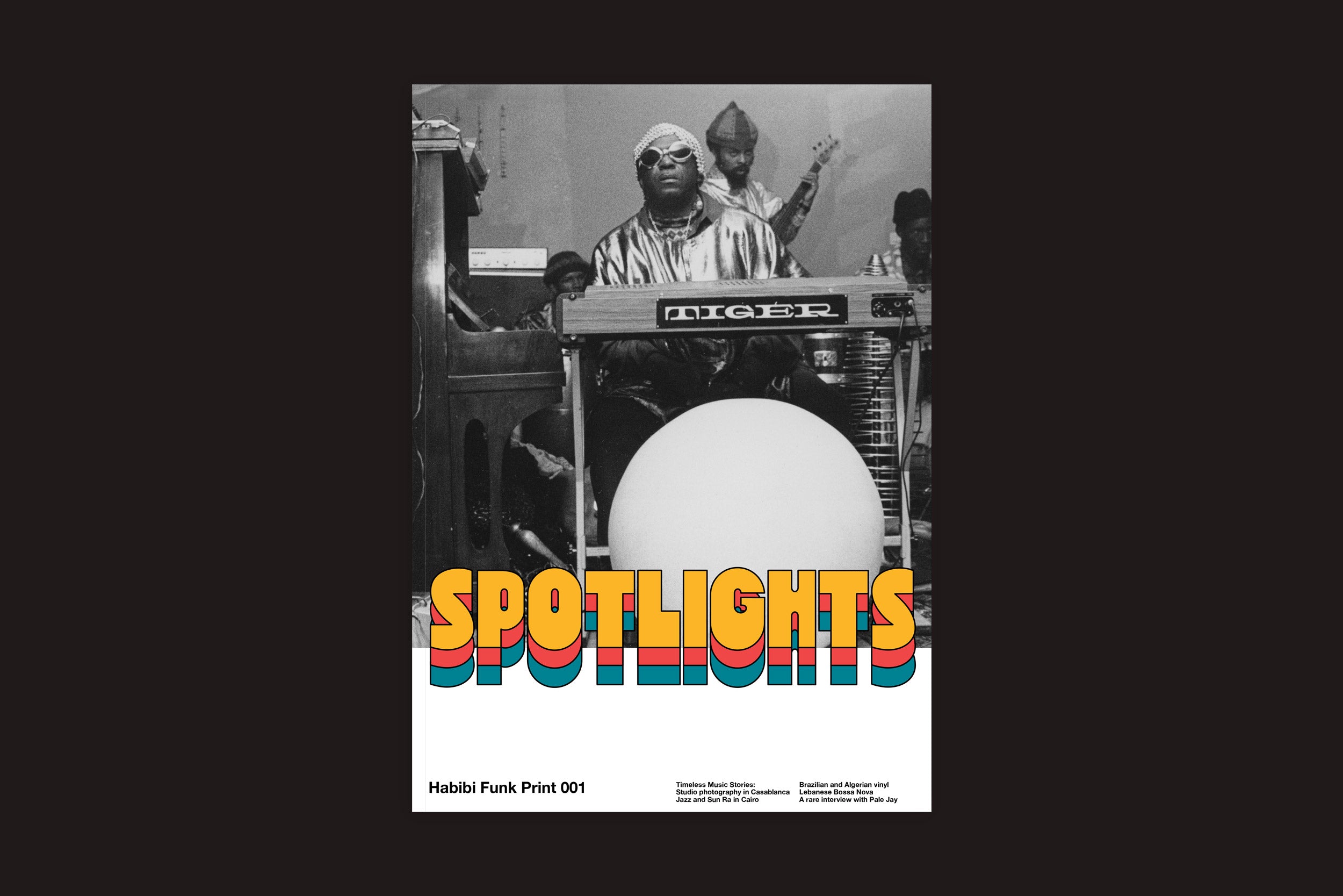 Foto em preto e branco de um músico com óculos escuros em um teclado Tiger, com outro músico atrás. "SPOTLIGHTS" em texto colorido sobrepõe a parte inferior. Abaixo: Habibi Funk Print 001: Revista Spotlights de Habibi Funk, celebrando a música árabe.