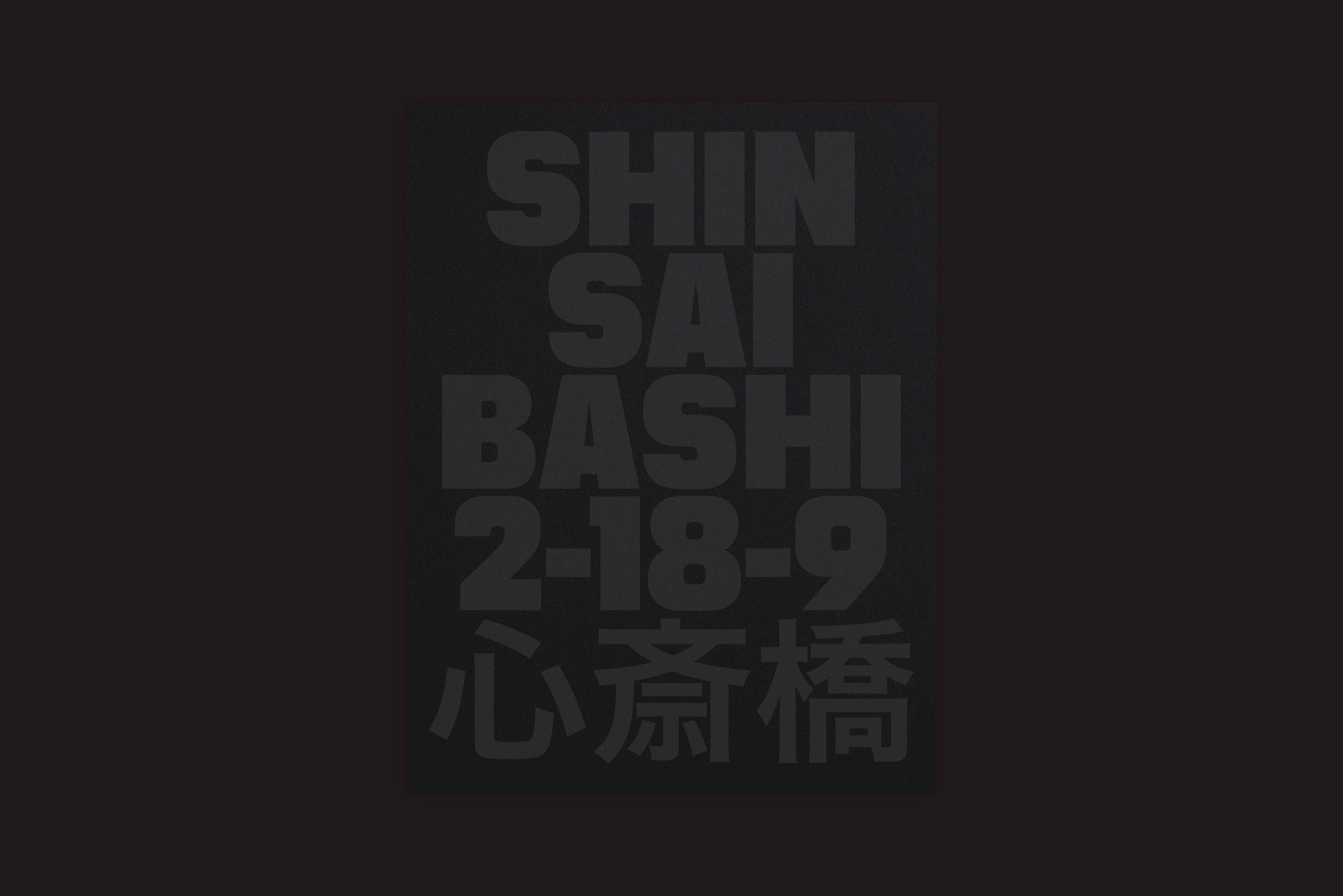 Um pôster preto de Selo Turvo intitulado "Lucas Gibson: Shinsaibashi 2-18-9" apresenta um texto em negrito cinza escuro com o endereço em letras maiúsculas e caracteres japoneses, em um fundo sombrio e inspirado em um subterrâneo.
