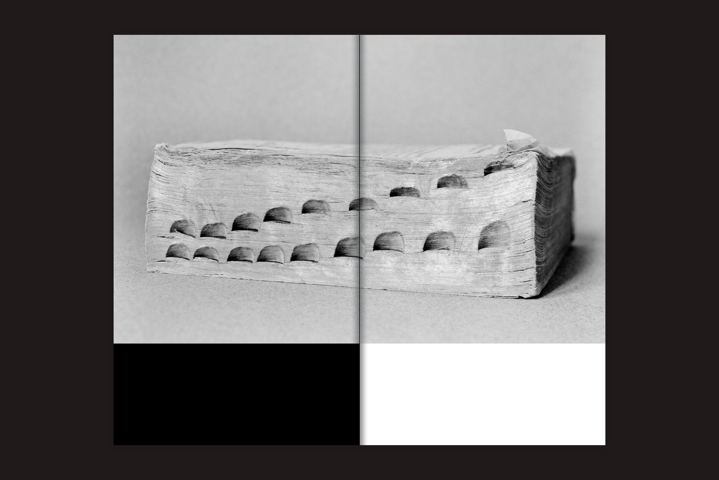 Um livro grosso e desgastado, com as abas do polegar visíveis, está fechado em uma superfície plana. A imagem em estilo de risografia apresenta quadrantes em preto, branco e tons de cinza - ideal para workshops sobre "Interrogating Site - São Paulo Syntax: v/a" do Selo Turvo.